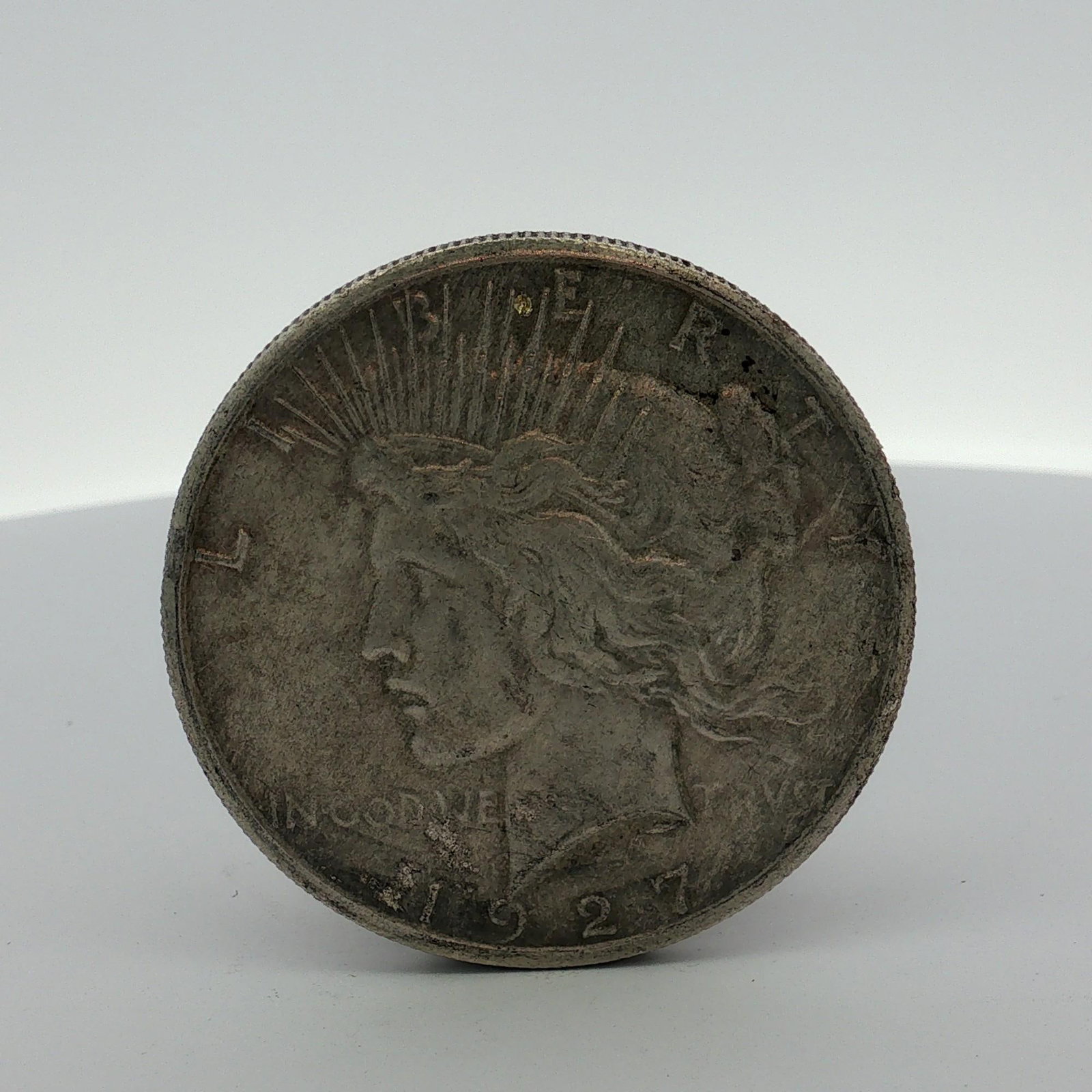 1927 US Peace Silver Dollar: US Peace silver dollar dated 1927 and struck at the Philadelphia Mint. The coin is composed of 90% silver and features the Anthony de Francisci design. The obverse displays the Liberty head with the i