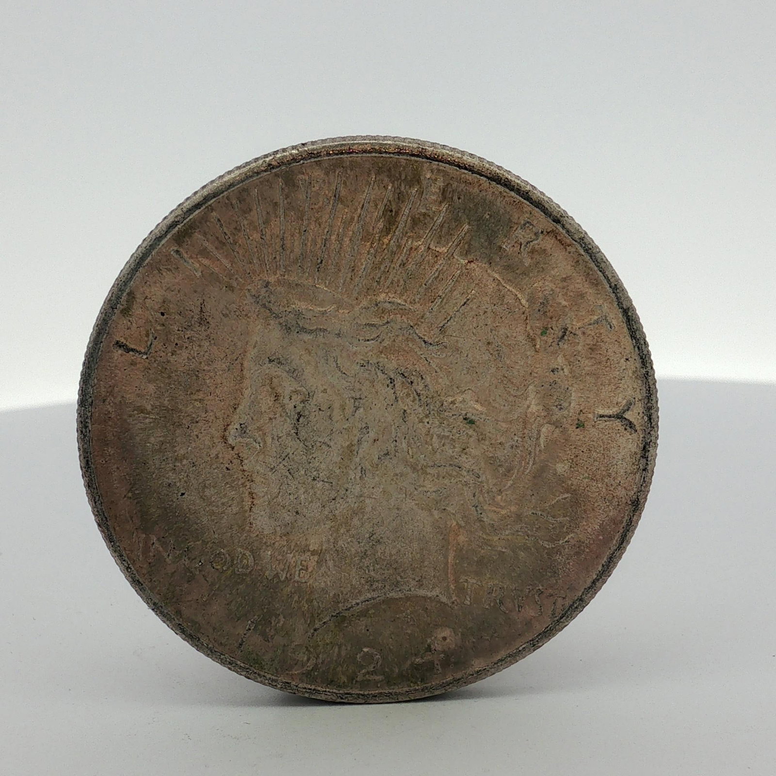 US 1924 Peace Silver Dollar: This US 1924 Peace silver dollar is composed of 90 percent silver and 10 percent copper. The coin features the standard Peace dollar design type on the obverse and reverse. The obverse displays the in