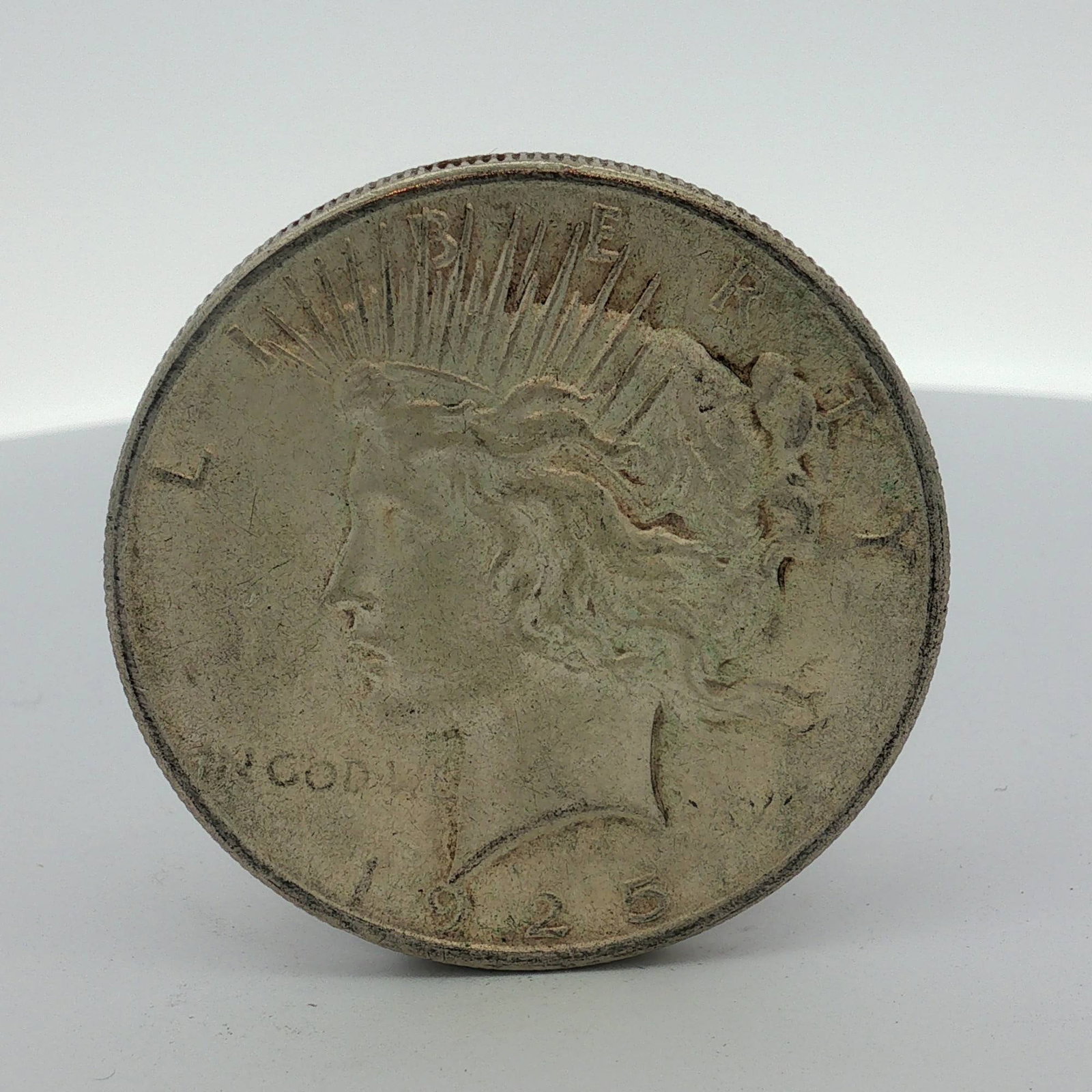 US 1925 Peace Silver Dollar: US 1925 Peace silver dollar struck at the Philadelphia mint. This coin is composed of a 90% silver and 10% copper alloy. The obverse features the Peace dollar design with the date 1925 and the legend