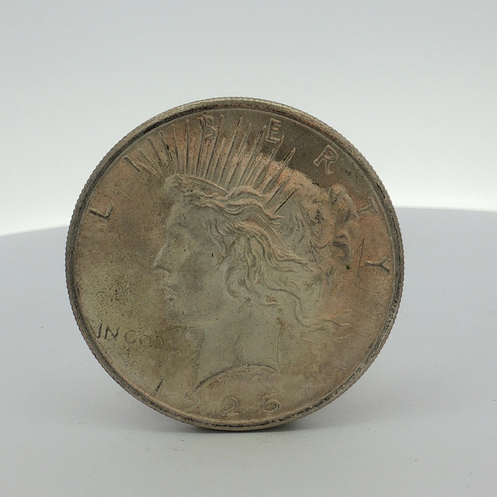 US 1925 Peace Silver Dollar: This US 1925 Peace silver dollar was struck at the Philadelphia mint. The coin is composed of 90 percent silver and 10 percent copper. The obverse features the Peace dollar design with a left-facing