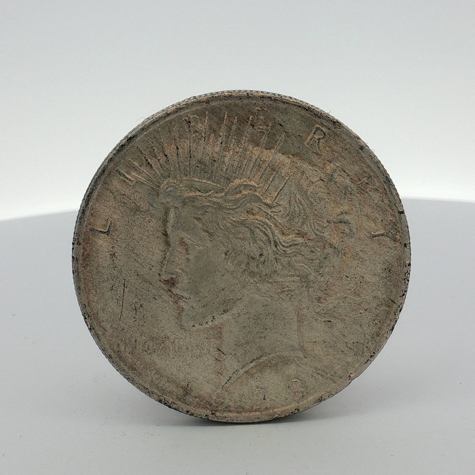US Peace Silver Dollar: This US Mint Peace dollar is struck in 90% silver and 10% copper. The obverse features the standard Peace dollar design including the motto IN GOD WE TRVST. The reverse displays the perched eagle