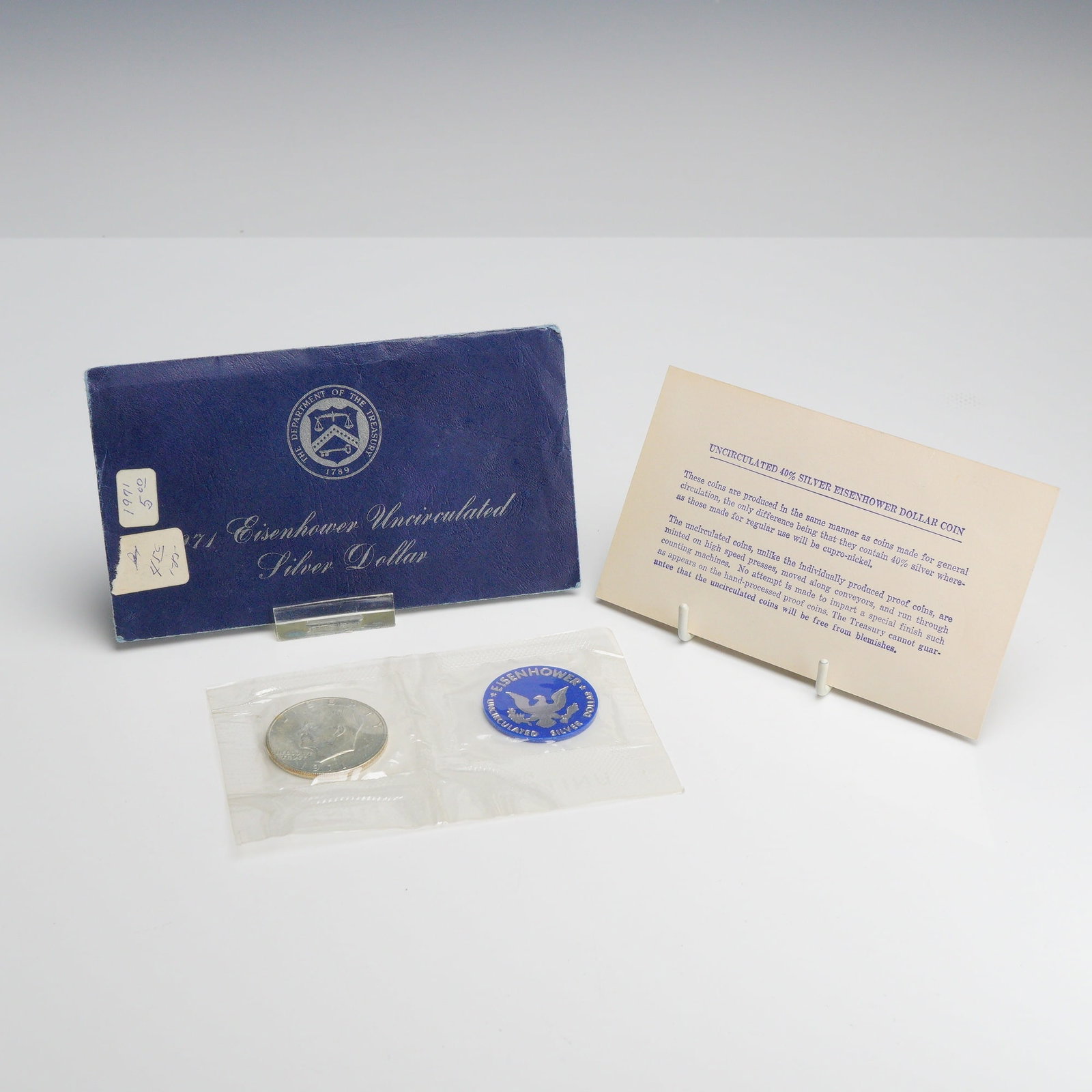 1971-S US Eisenhower 40% Silver Dollar Uncirculated Blue Envelope: This 1971-S Eisenhower 40% silver dollar was produced by the US Mint at the San Francisco facility. The coin features the Dwight D. Eisenhower obverse and the Apollo 11 commemorative reverse. It is