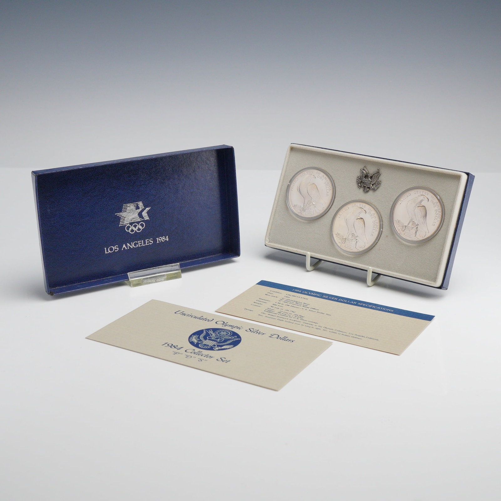 1984 US Olympic Silver Dollar P, D, and S Uncirculated Three-Coin Set: This collector set contains three 1984 US silver dollars issued to commemorate the Los Angeles Olympic Games. The set includes uncirculated specimens from the Philadelphia (P), Denver (D), and San