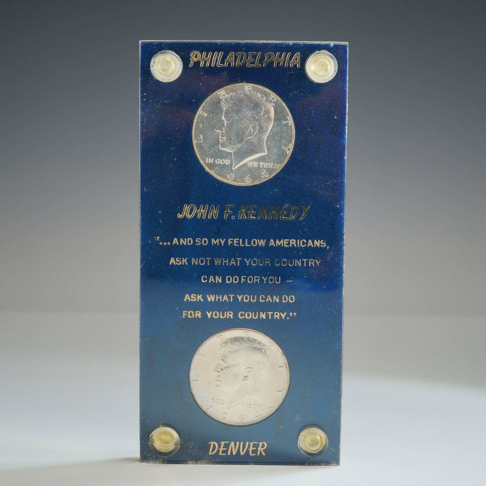 A Pair of 1964 US Kennedy Silver Half Dollars in Memorial Holder: This lot features a pair of 1964 US Kennedy silver half dollars, comprising one specimen from the Philadelphia Mint and one from the Denver Mint. These coins represent the first year of issue for the 