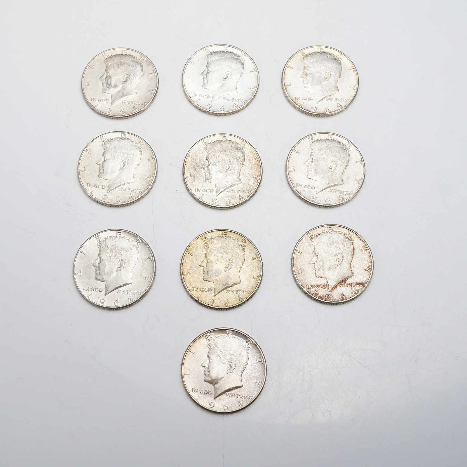 A Collection of Ten 1964 US Kennedy Half Dollars: This lot consists of ten US 1964 Kennedy half dollars with a total $5.00 face value. Struck at the Philadelphia Mint, these coins are composed of 90% silver and 10% copper. The obverse features the Ke