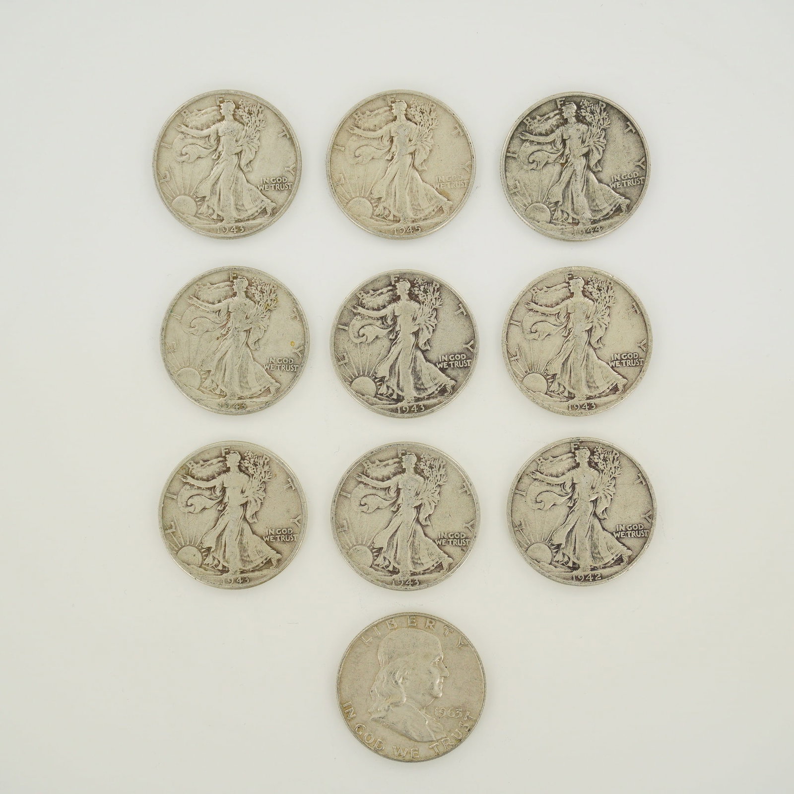 A Collection of 10 US Silver Walking Liberty and Franklin Half Dollars: A collection of 10 US silver half dollars, including nine Walking Liberty examples and one Franklin example. The Walking Liberty coins feature the following dates and mint marks: one 1942, one 1943, f