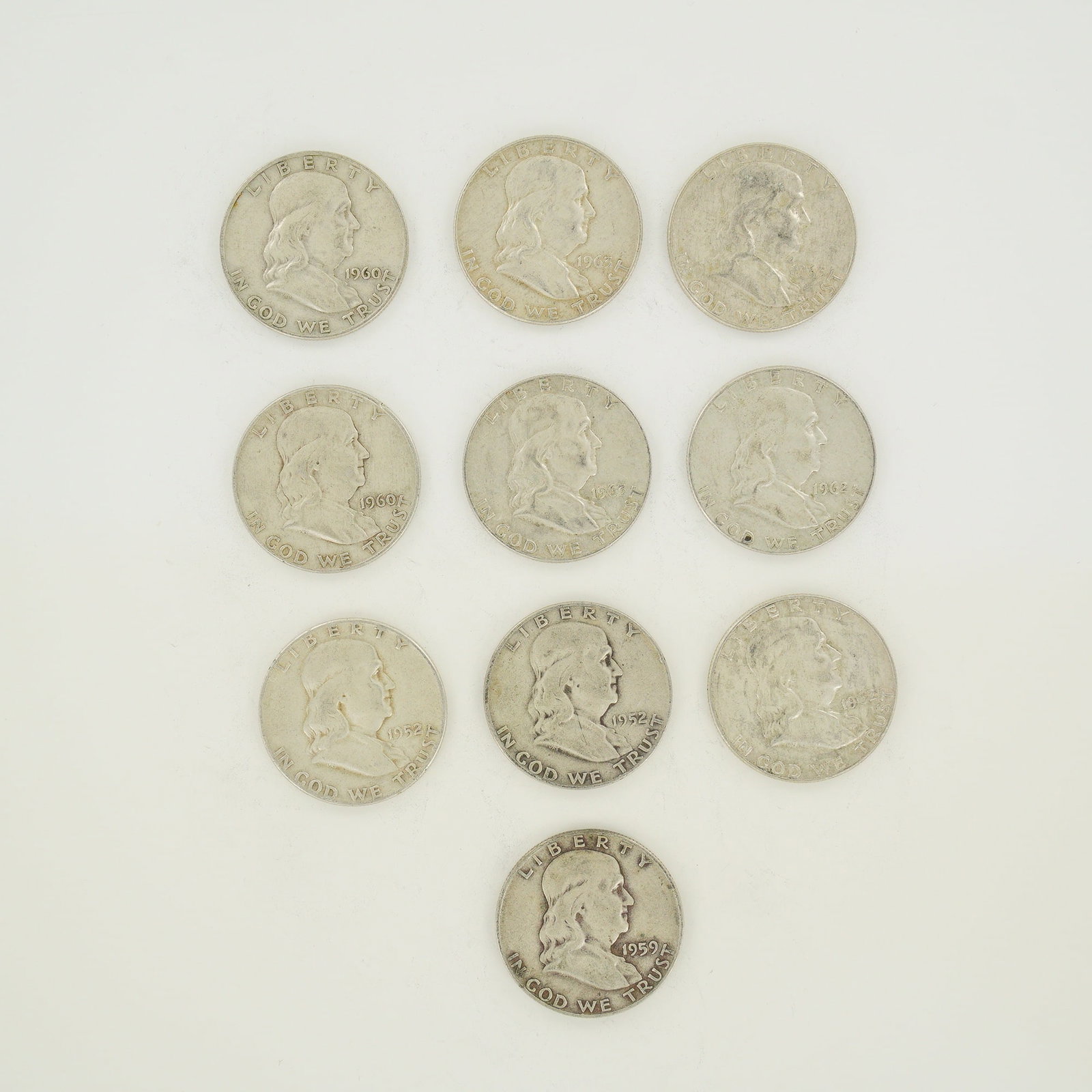 A Collection of Ten US Franklin Half Dollars, $5.00 Face Value: A collection of ten US Franklin half dollars dated between 1952 and 1963, representing a $5.00 face value. These coins are struck in 90% silver with reeded edges. The assortment includes issues from t