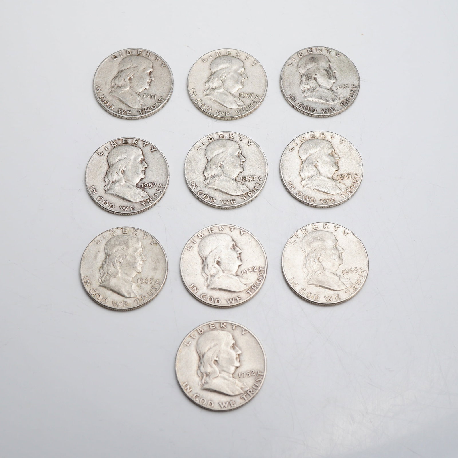 Ten US 1951-1963 Franklin 90% Silver Half Dollars: The assortment includes two coins from 1951, two from 1952, four from 1957, and two from 1963. Mint marks for Denver (D) are present. The design features the Franklin obverse and the Liberty Bell