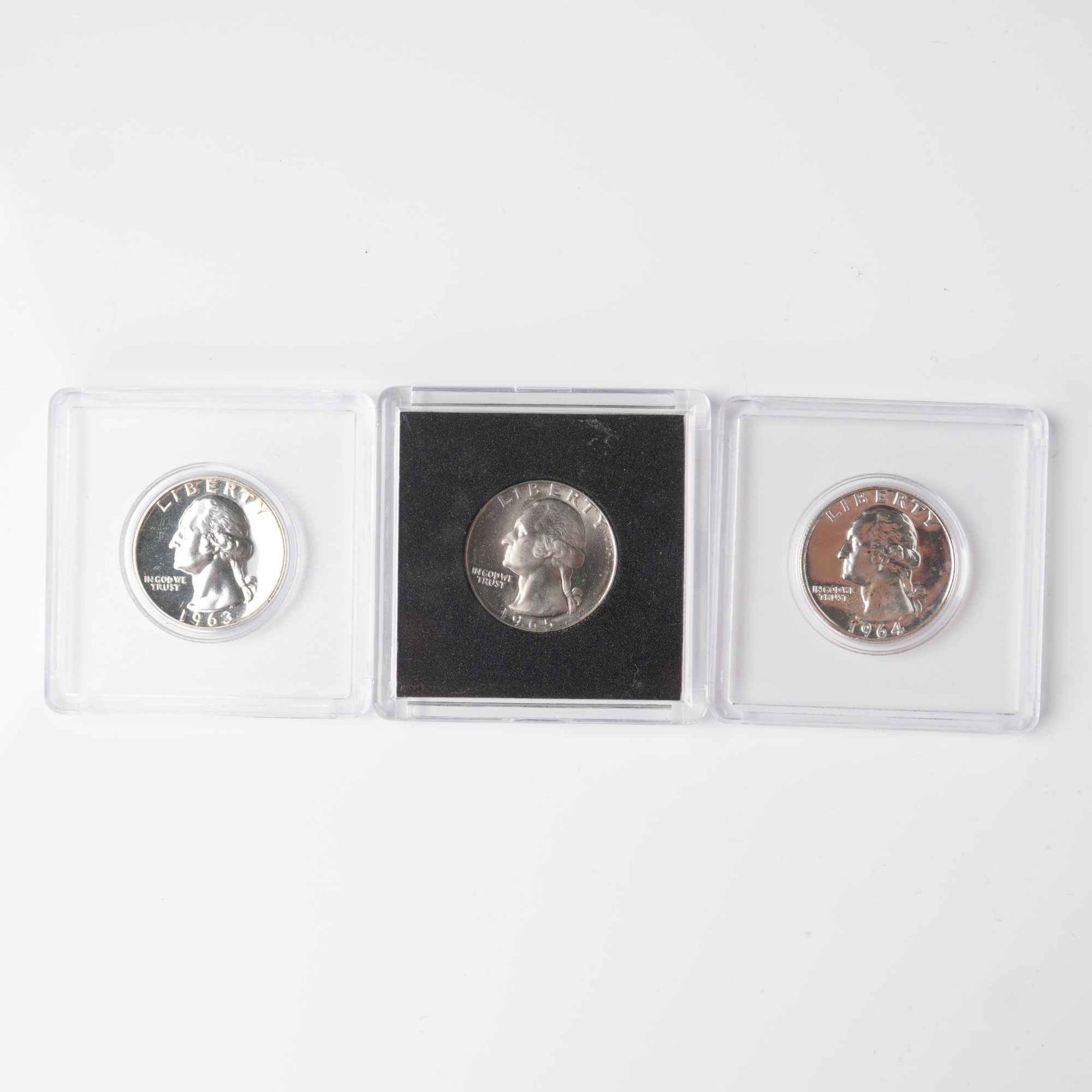 3pc 1963, 1964, & 1965 Washington Quarters: A trio of United States Washington quarters dated 1963, 1964, and 1965, each bearing the iconic portrait of George Washington designed by John Flanagan. The obverse shows Washington facing left with