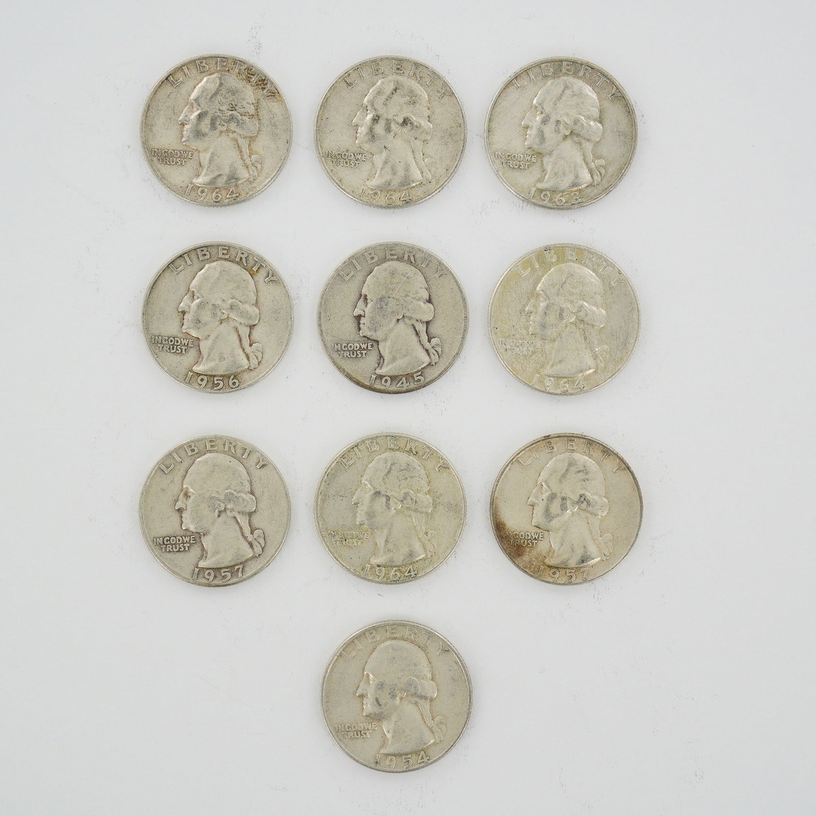Ten US Silver Washington Quarters, 1945-1964: A collection of ten US Washington Quarters struck in 90% silver. This mixed date bag of coinage includes 1945, 1954, 1956, 1957, 1963, and 1964 specimens. The coins feature the Washington type