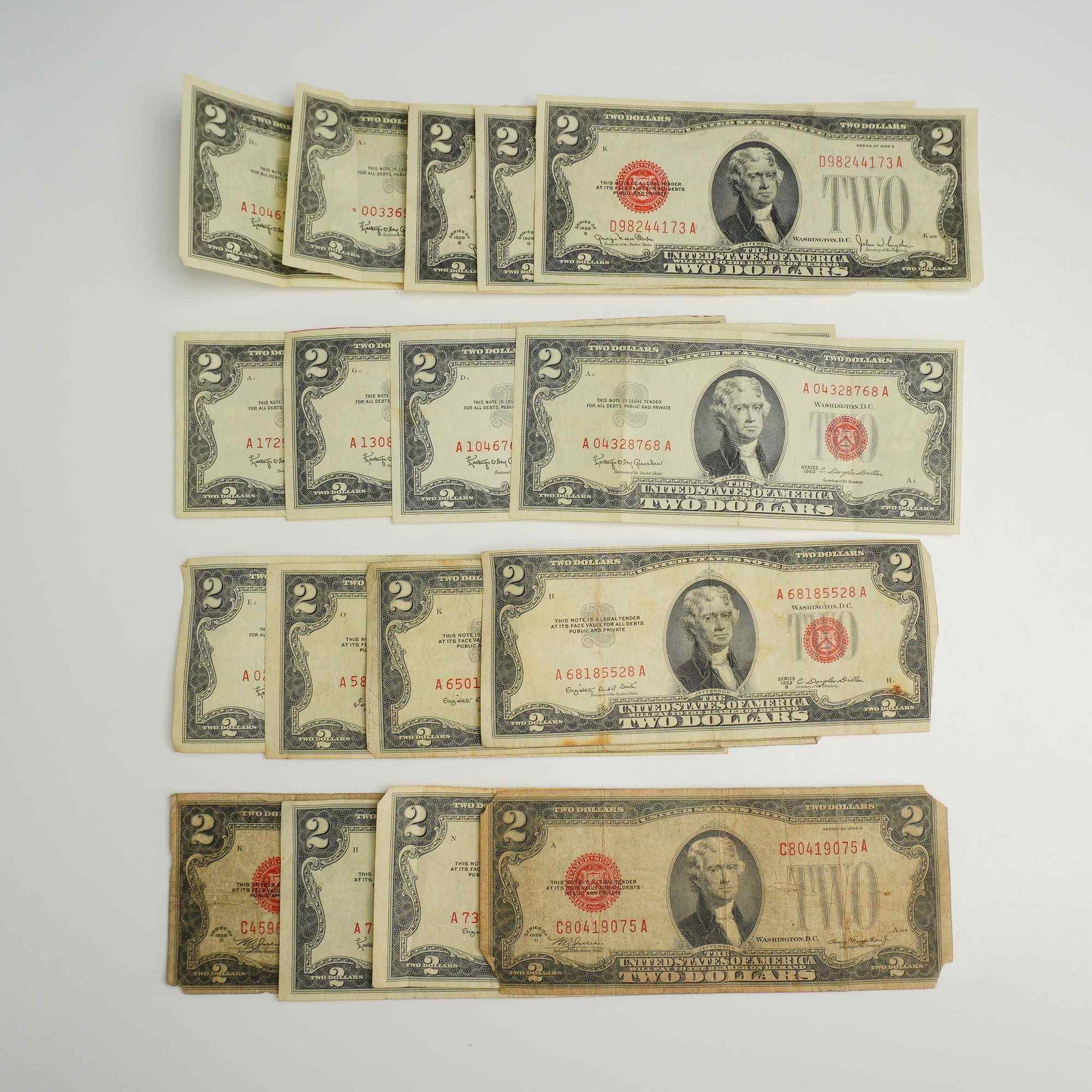 A Collection of Banknotes Including Vintage US $2.00 Bills and Canadian $1 Notes: This assortment of North American paper currency includes multiple US $2 United States Notes and Canadian $1 banknotes. The US notes are Legal Tender issues characterized by red treasury seals and