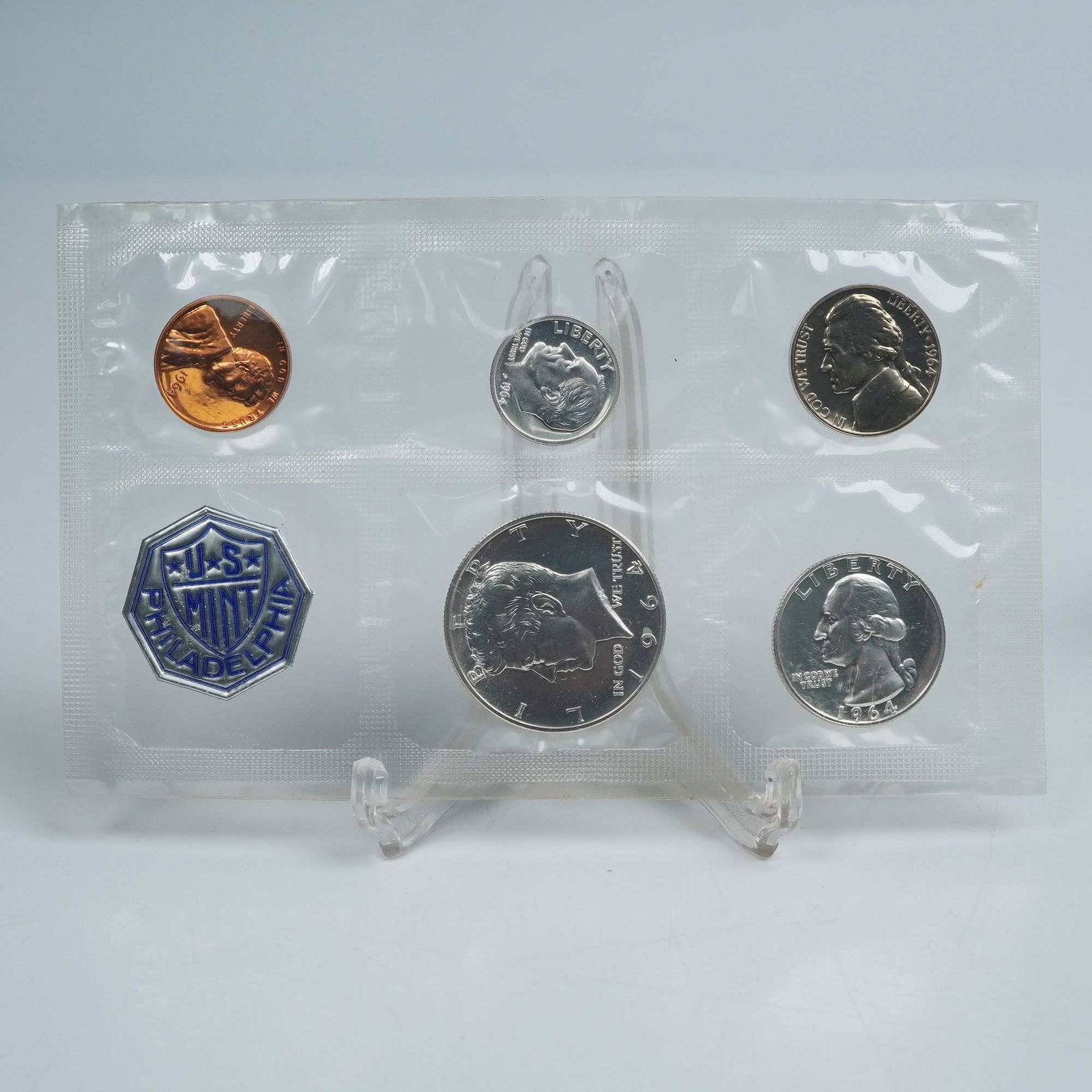 1964 Set of 6 U.S. Mint Philadelphia Proof Coins: A complete 1964 Philadelphia Mint Proof Set featuring six coins sealed in Original Government Packaging (OGP). The set includes the Lincoln Cent, Jefferson Nickel, Roosevelt Dime, Washington Quarter, 