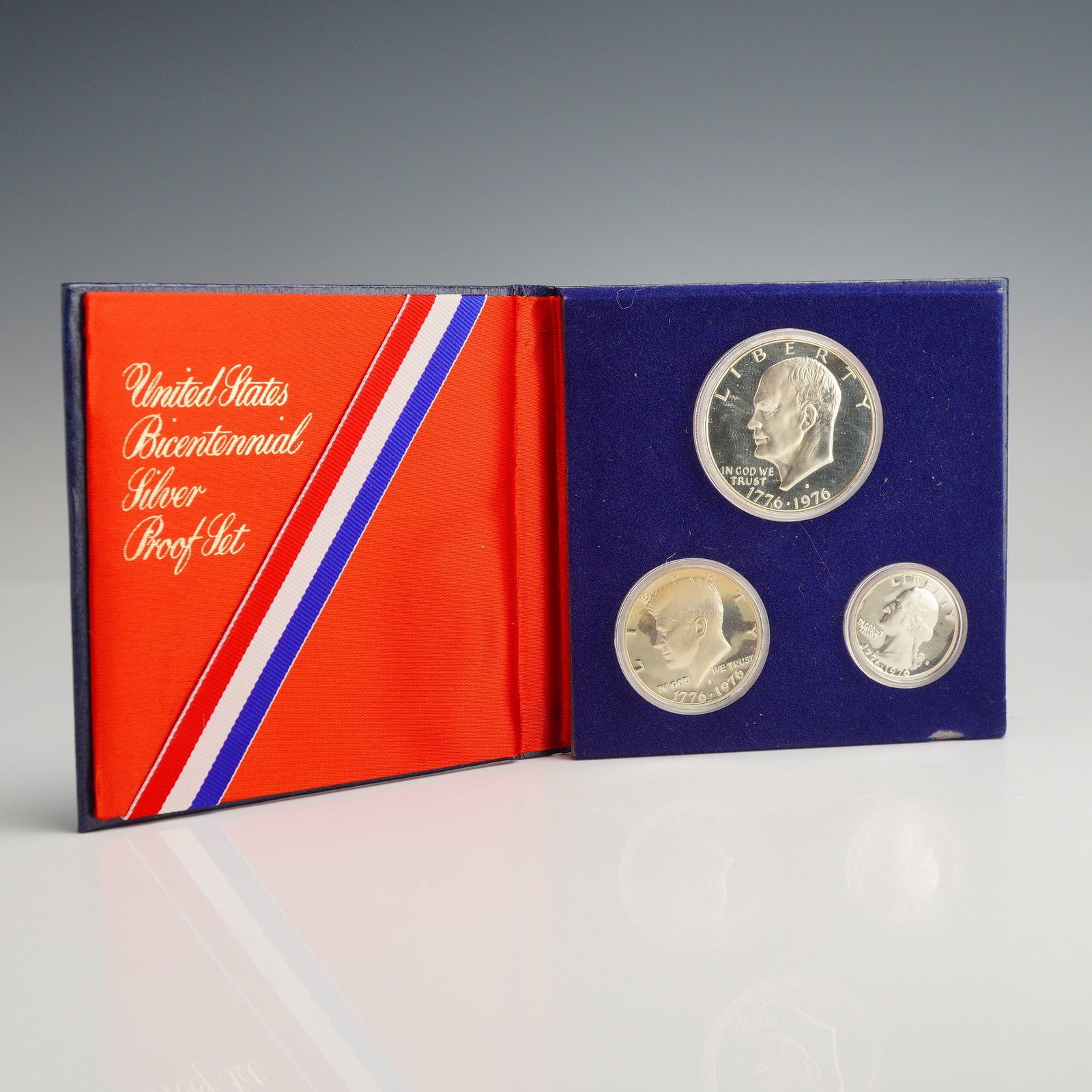 US 1976 Bicentennial Silver Proof Set: This three-coin US 1976 Bicentennial silver proof set is presented in its original government packaging. The set includes a Washington quarter, a Kennedy half dollar, and an Eisenhower dollar, all