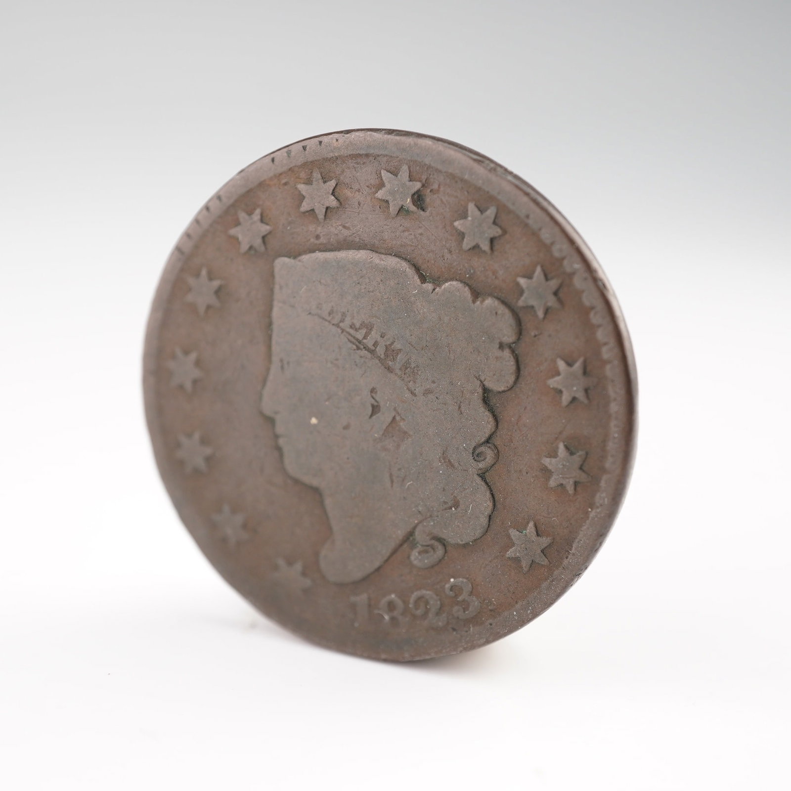 1823 Liberty Head Large One Cent: An early 19th century United States large cent featuring the Liberty Head design, also known as the Coronet Head type. The obverse depicts a left-facing profile of Lady Liberty wearing a coronet inscr