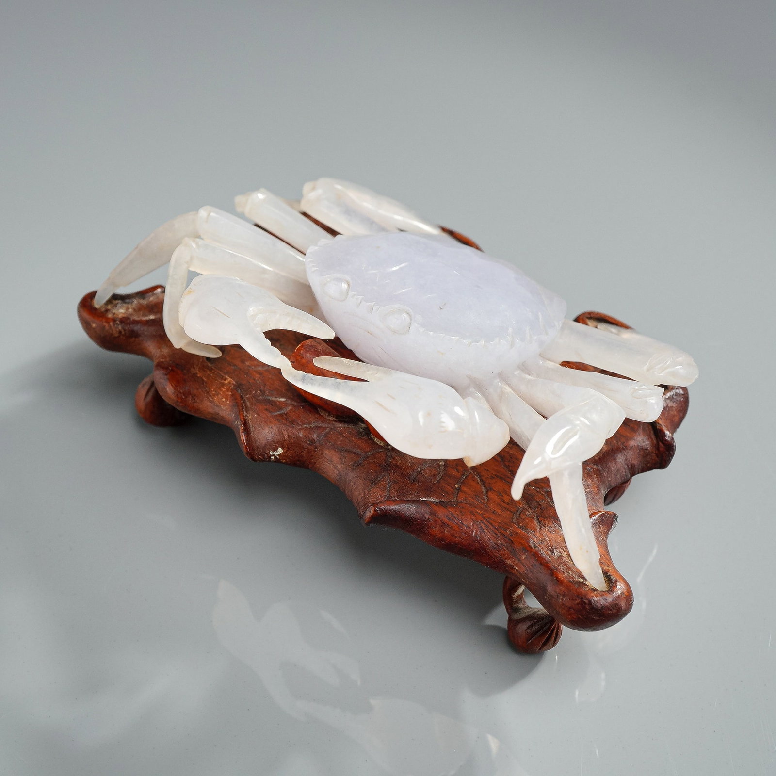 Carved White Stone Crab Figurine with Wooden Stand: This lot features a naturalistically carved stone crab rendered in a translucent material with hues ranging from pale white to soft lavender-purple. The figure is finely detailed with a polished carap