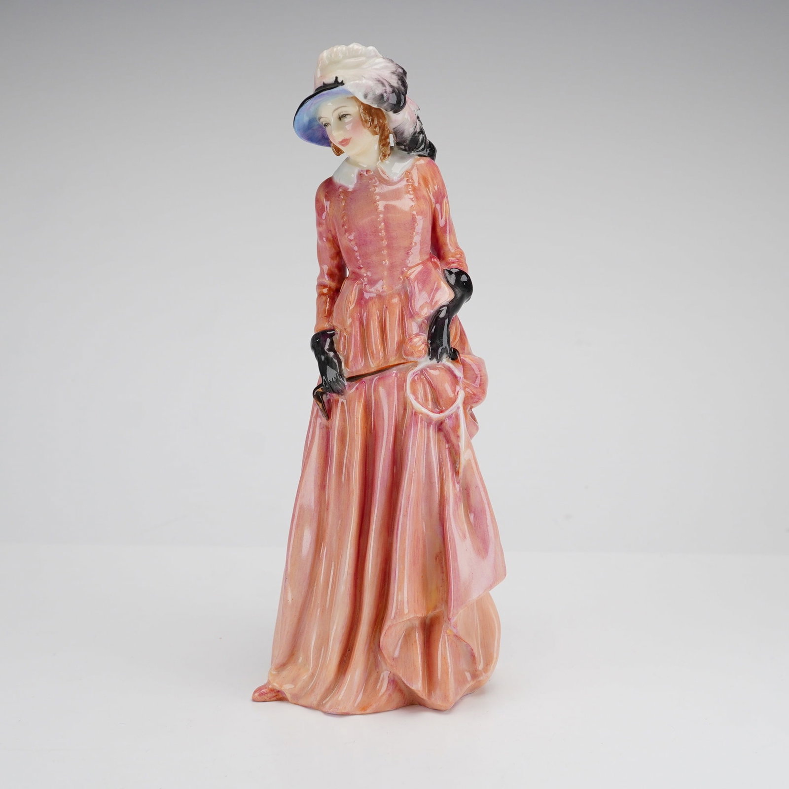 Royal Doulton, Maureen HN1770, Porcelain Figurine: A Royal Doulton glazed bone china figurine titled Maureen, model number HN 1770, designed by Leslie Harradine. The standing female figure is depicted in an early 19th-century style riding habit, featu