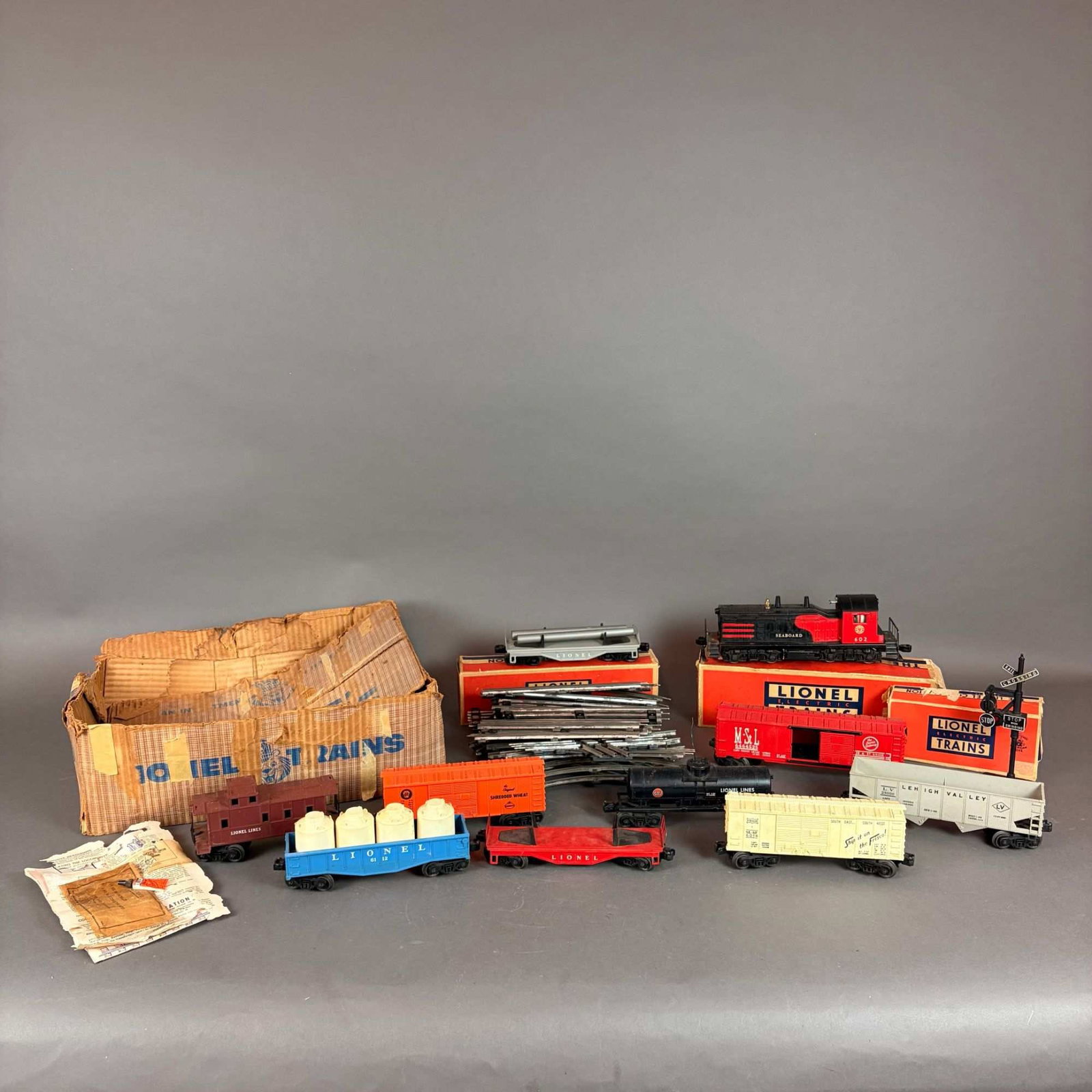 A Collection of Lionel Postwar O-Gauge Model Trains and Accessories in Original Boxes: This extensive postwar Lionel O-gauge train set is centered around a Seaboard NW-2 diesel switcher locomotive featuring a striking red and black body and a sturdy die-cast metal chassis. The rolling s