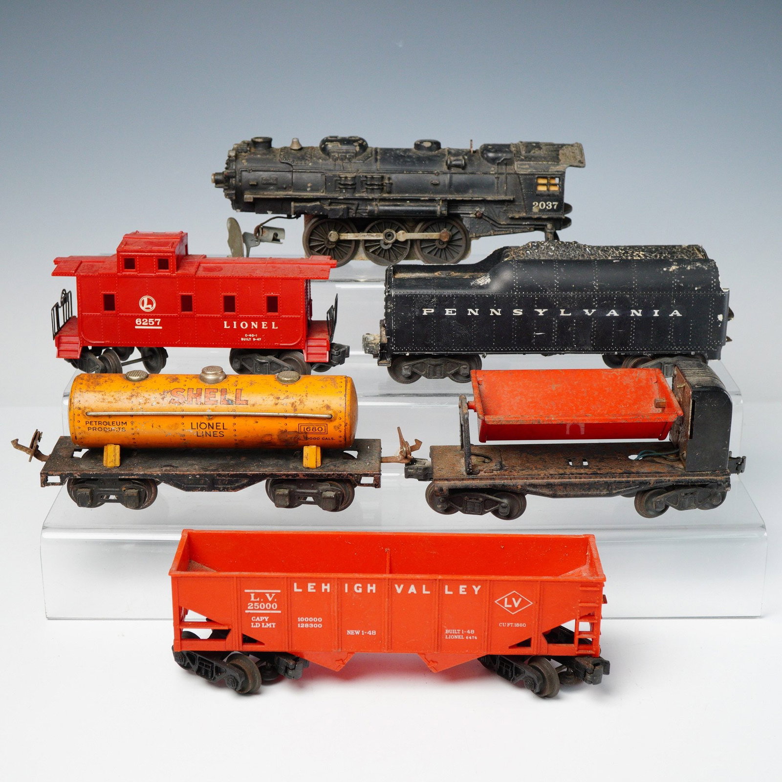 6pc Lionel Postwar O27 Model Railroad Pieces: A collection of six pieces of vintage American Lionel '027' gauge model railroad equipment, dating to the Postwar era. The lot includes one black steam locomotive marked '2037', one black coal tender 