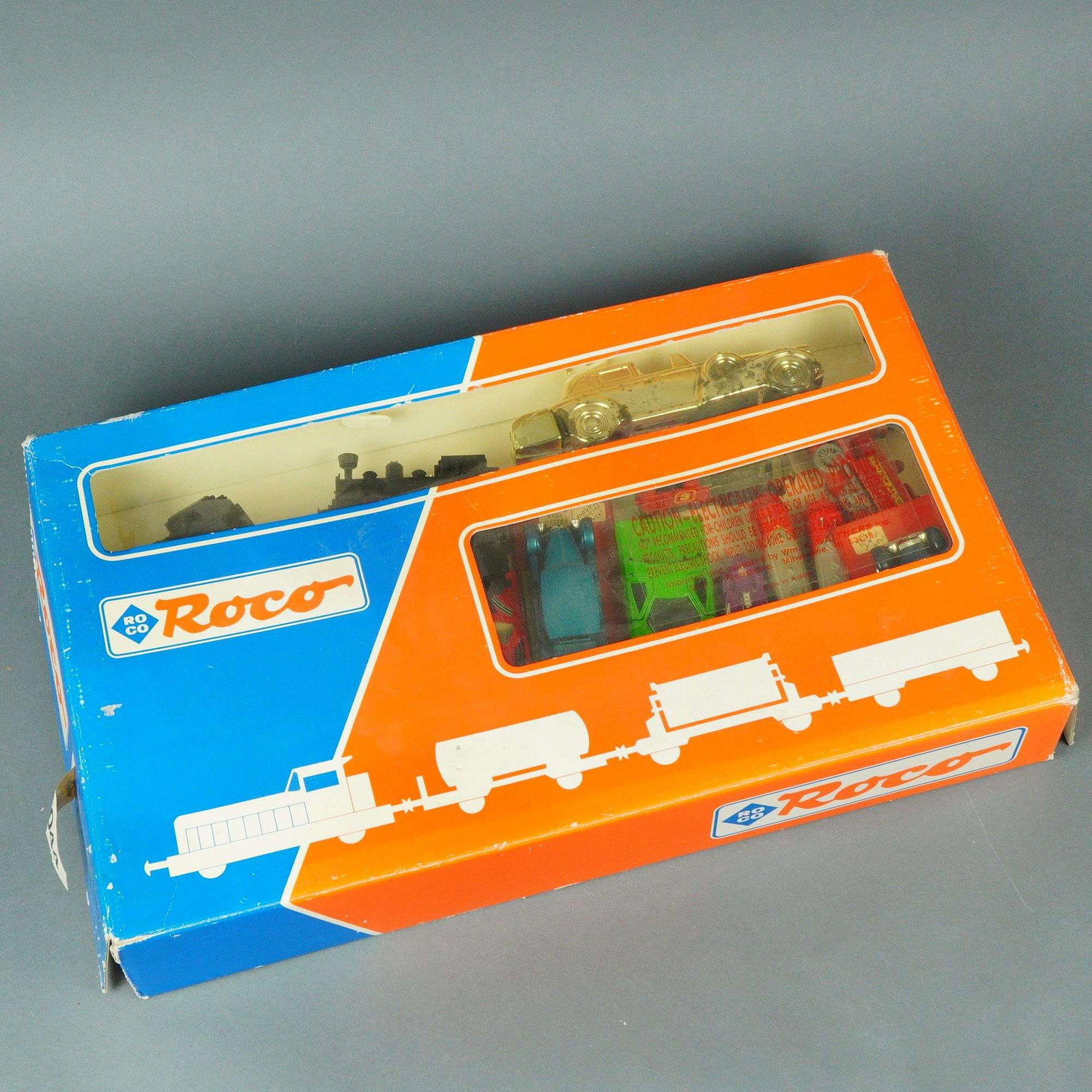 Assortment of Roco and Mixed Die-Cast Model Vehicles and Railway Stock: The lot comprises a collection of 32 die-cast miniature vehicles and model railway components. The centerpiece is a Roco-branded model train and vehicle set, identified through web consensus as simila