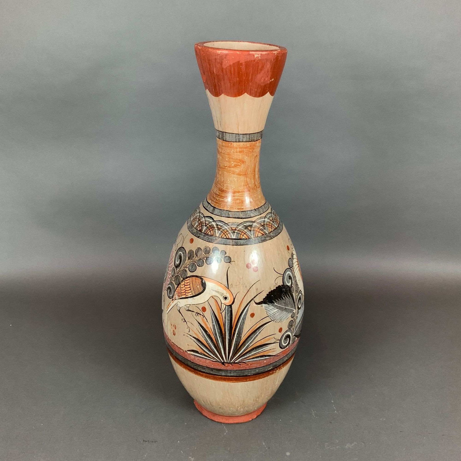 Mexican Tonala Hand Painted Burnished Earthenware Floor Vase with Bird Motifs: This large Mexican Tonala pottery vase is crafted in the traditional barro brunido or burnished clay style. The piece features a bottle-form silhouette with a flared scalloped rim, a long tapered neck
