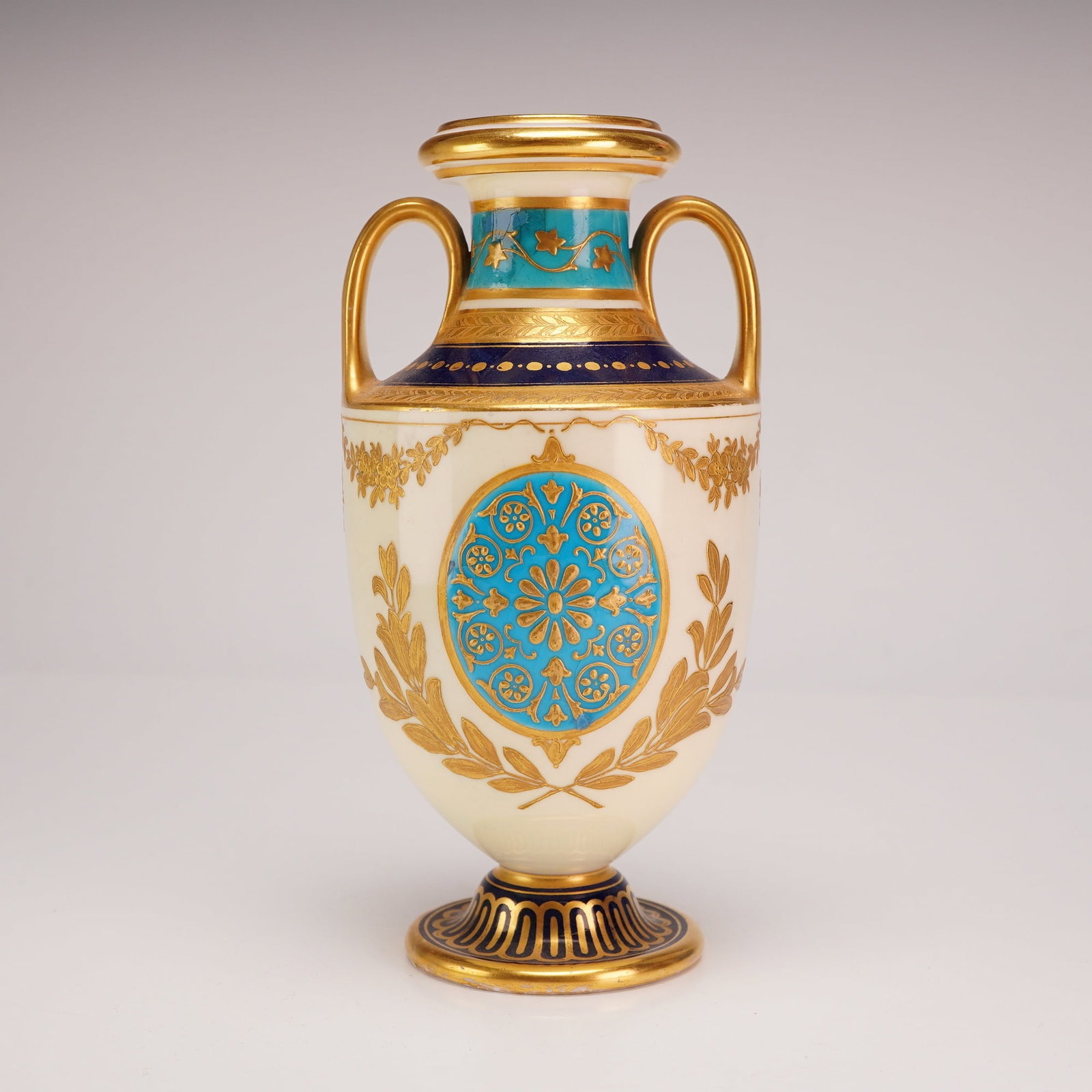 Mortlock's Oxford Street English Neoclassical Porcelain Vase: This English porcelain vase, produced in the late 19th century, bears the retail mark for Mortlock's of Oxford Street, London. The piece is constructed in a two-handled amphora form featuring an