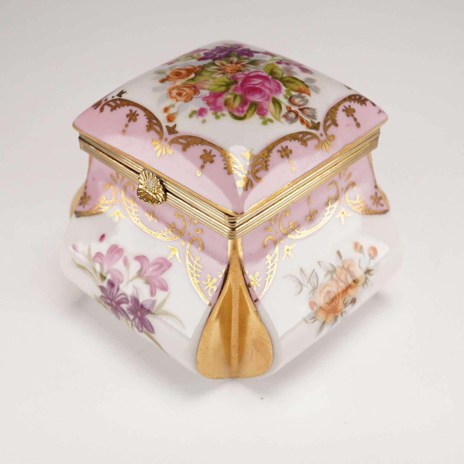 Norleans Japan Hand-Painted Porcelain Trinket Box: A Norleans hand-painted porcelain trinket box, manufactured in Japan. This decorative lidded box is crafted from white porcelain with hand-painted floral motifs and gilt metal fittings. The