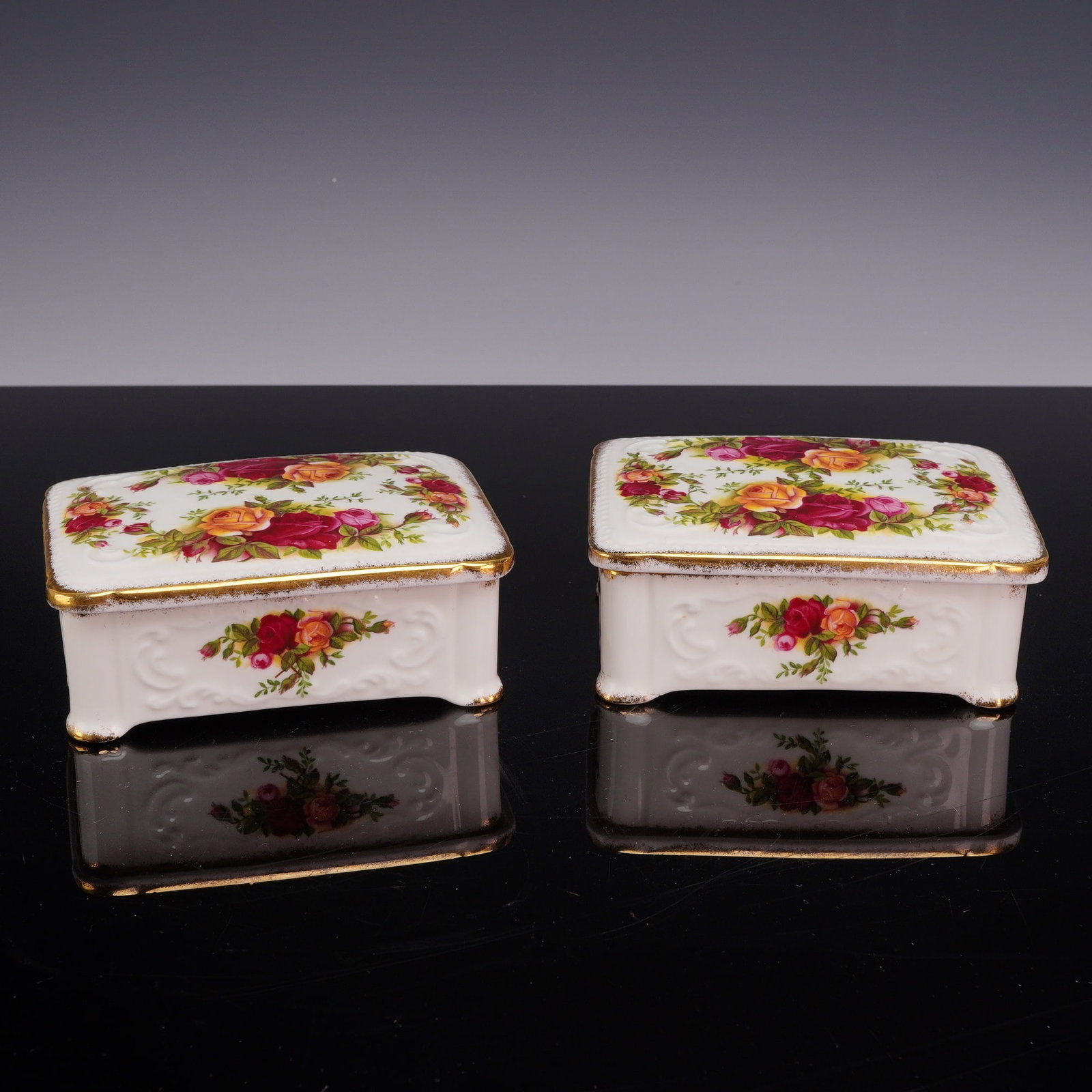 Pair of Royal Albert Bone China Lidded Trinket Boxes, Old Country Roses: A pair of rectangular lidded trinket boxes produced by Royal Albert in the Old Country Roses pattern. Each box is constructed from bone china and features a lobed body resting on four molded scroll fe
