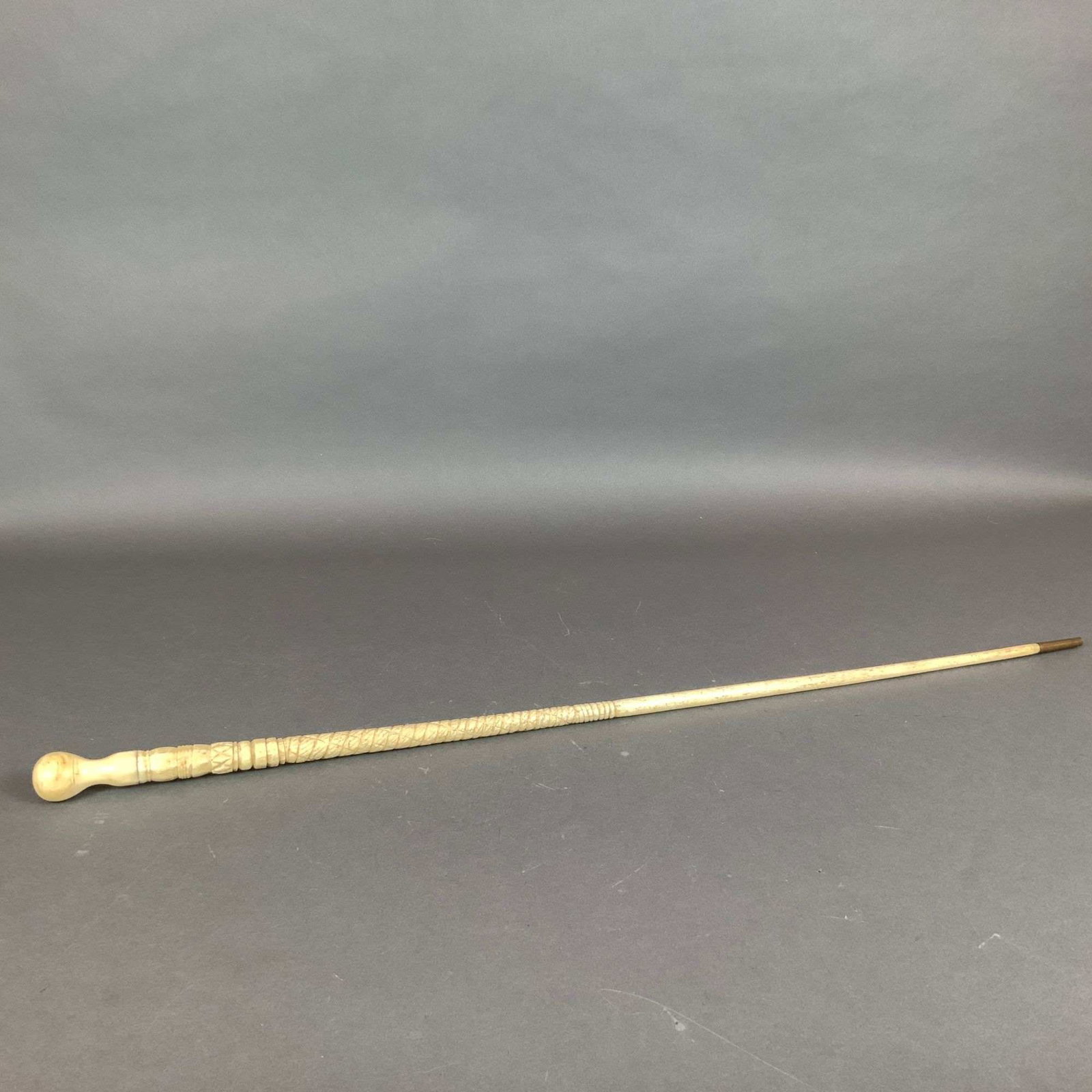 Carved Bone Walking Cane: This item is a sailor-made walking cane featuring a carved bone handle and metal end. The construction features a multi-segmented upper shaft with various decorative styles including turned rings, a