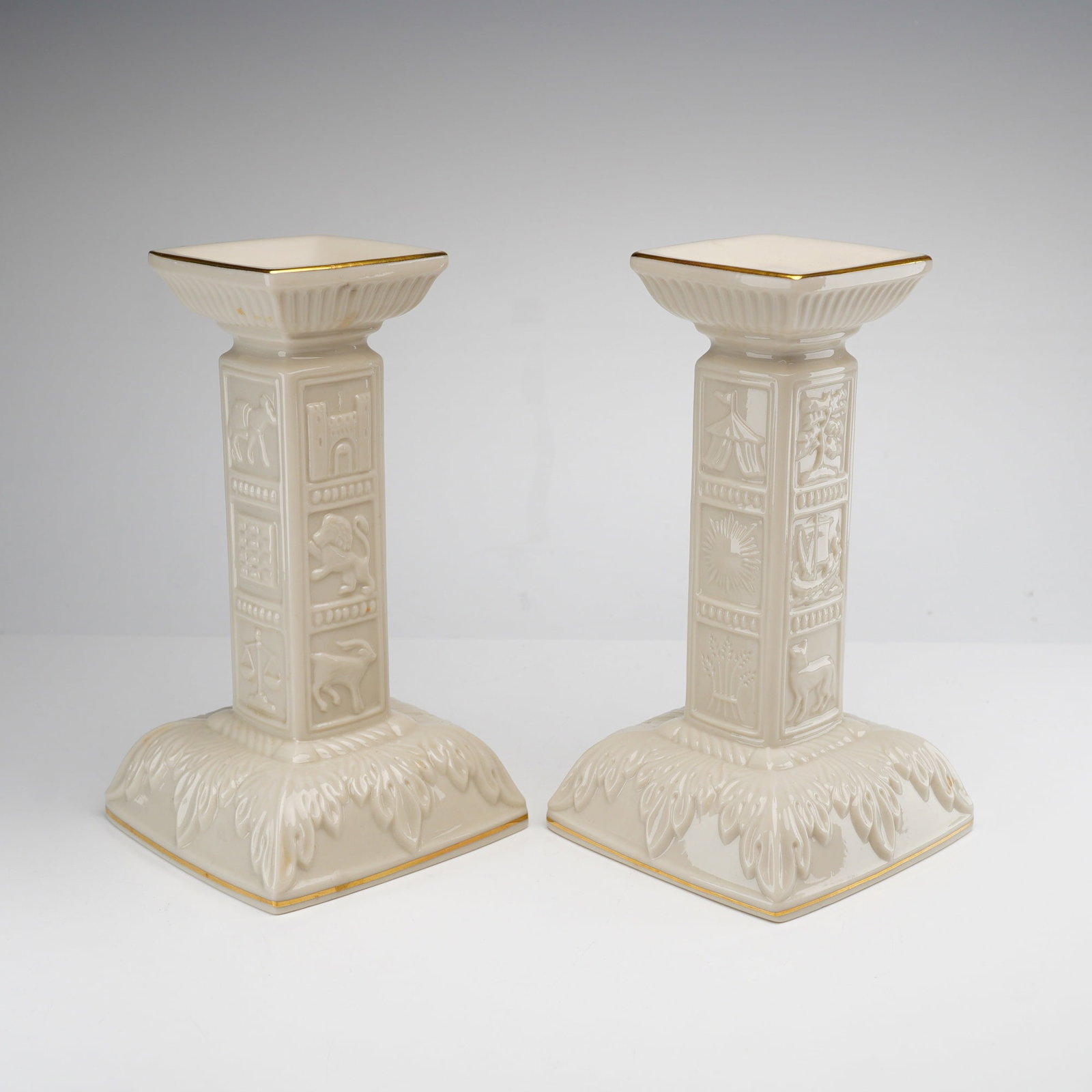 Pair of Lenox Porcelain Sabbath Candlesticks with 22k Gold Gilding: This pair of Lenox ivory-toned porcelain Shabbat candlesticks is part of the manufacturer's Judaic Collection. Each candlestick features a square-column shaft with relief-molded panels on all four
