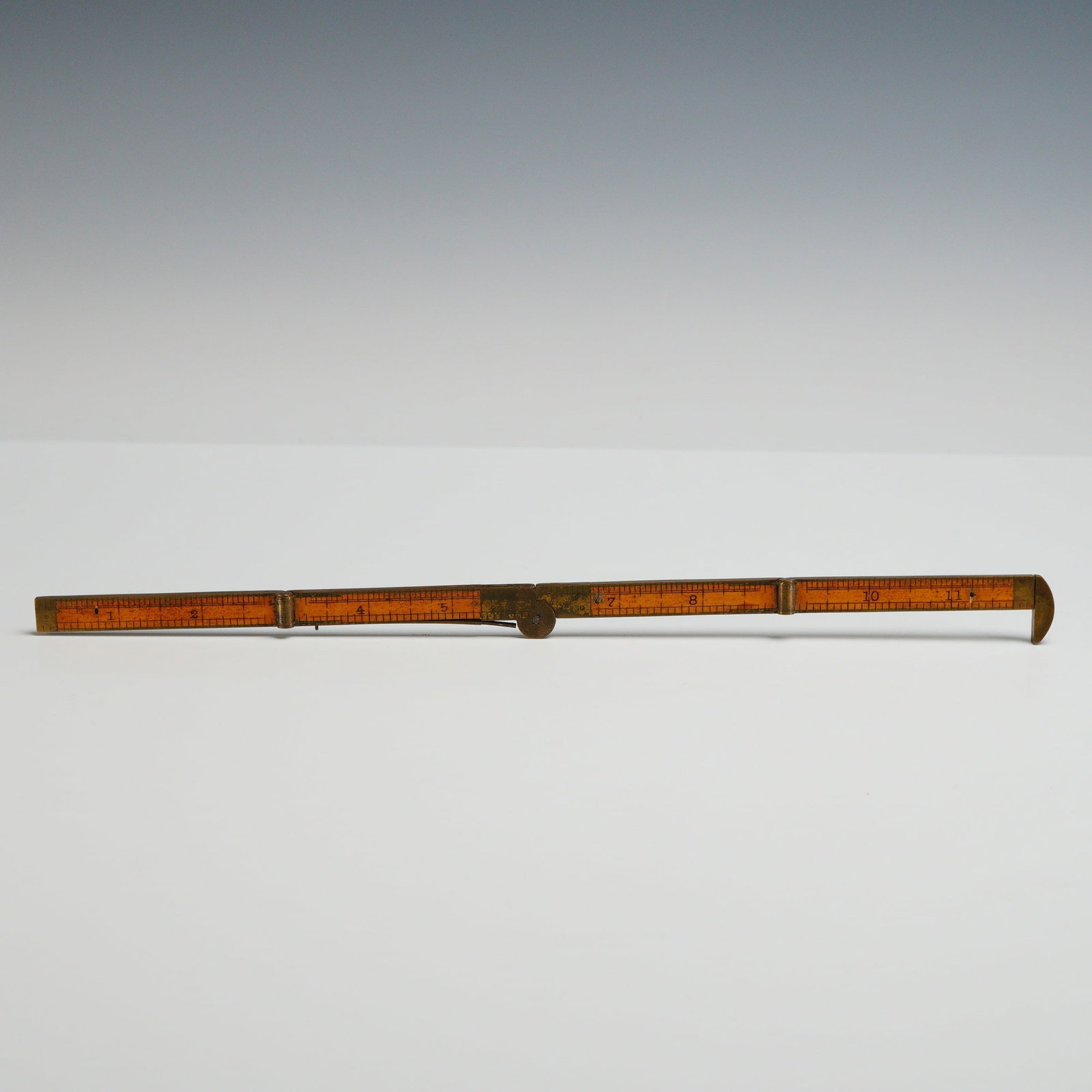 Boxwood and Brass Four-Fold 12-Inch Caliper Rule: This folding ruler is constructed from boxwood with brass furniture, including the main hinges, end caps, and an integrated sliding caliper. The instrument features a traditional four-fold design