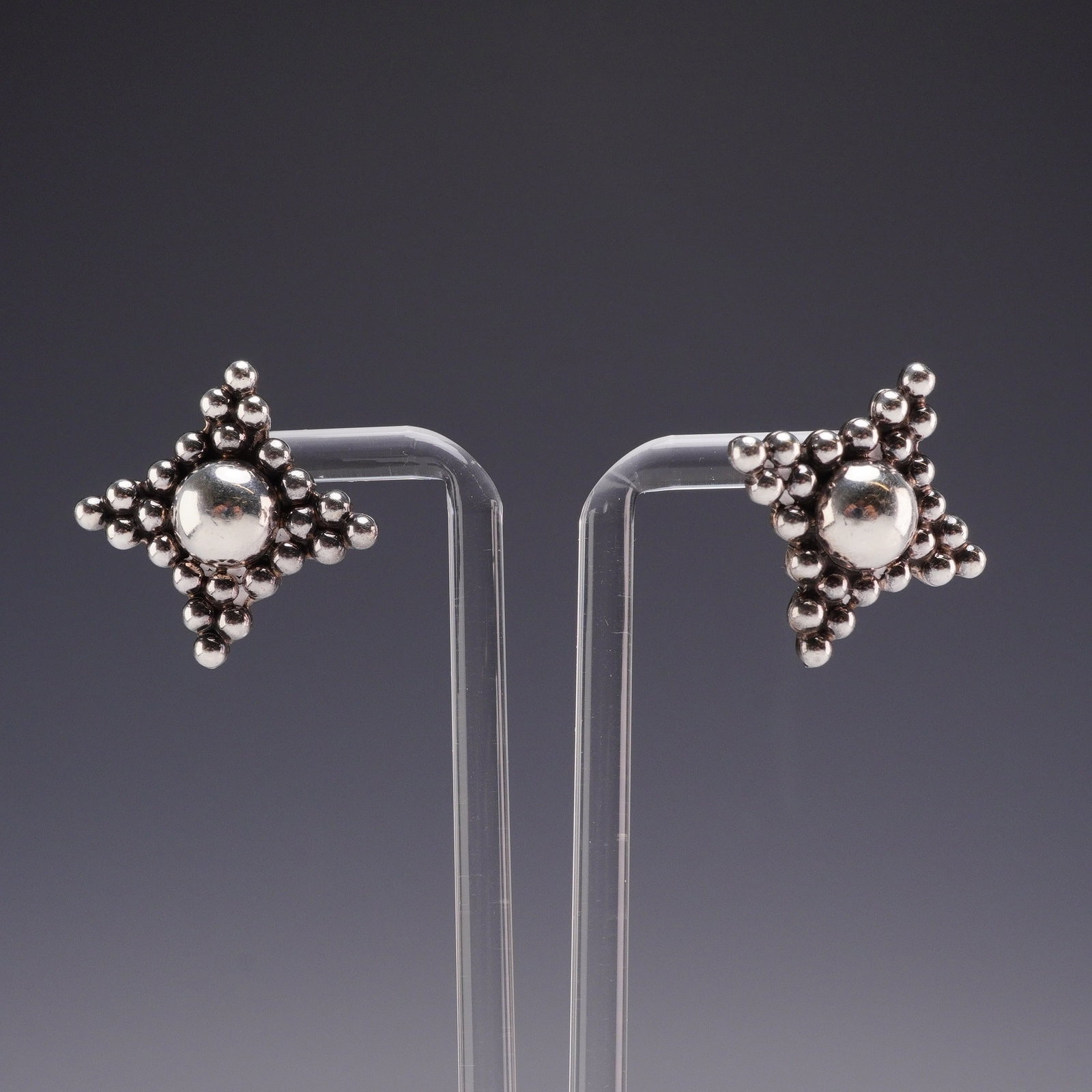 Mexican Sterling Silver Bubble Statement Stud Earrings: This pair of sterling silver stud earrings were crafted in Mexico. Each earring features a central polished dome surrounded by a border of graduated silver granulation beads arranged in a