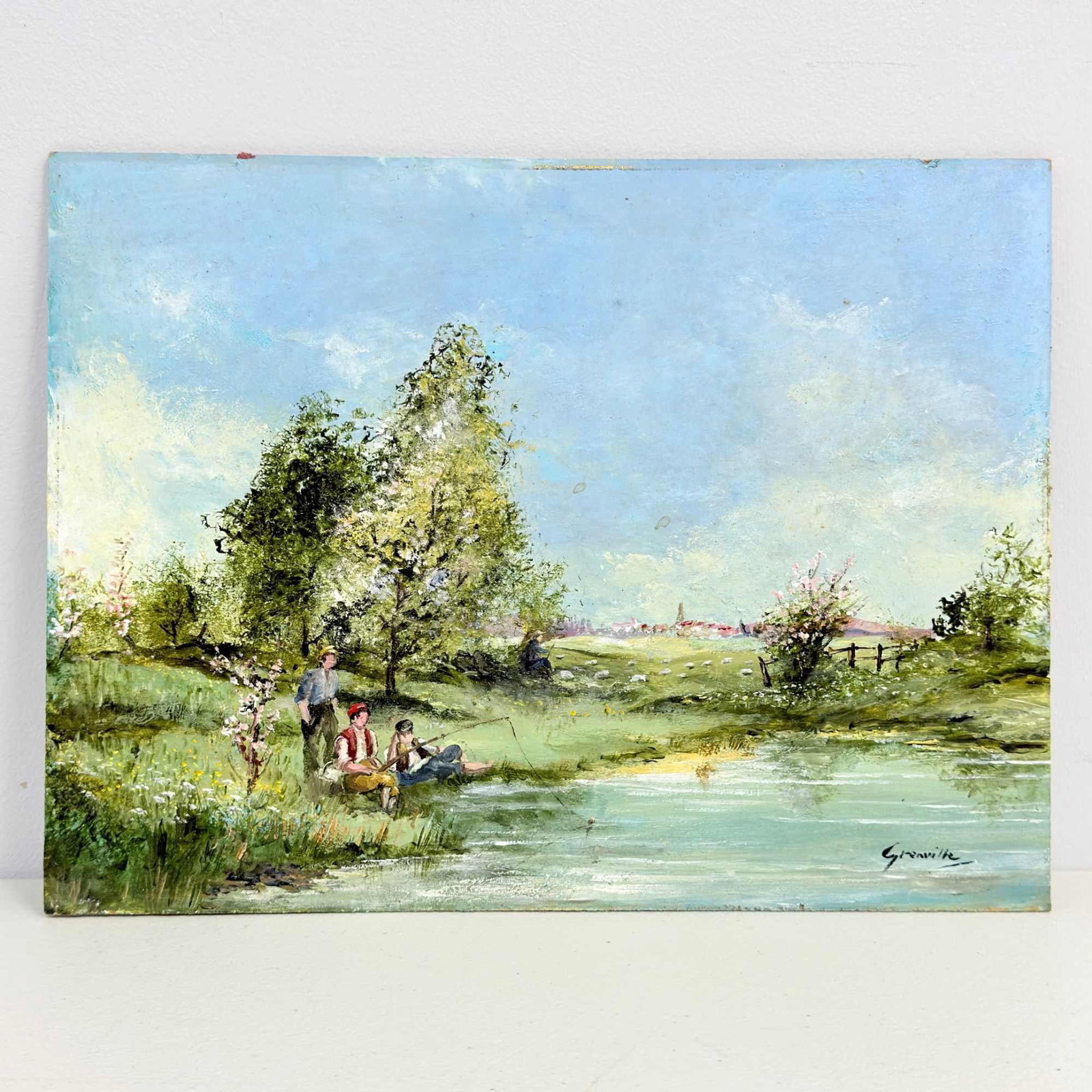 Jean Grenville, A Spring Day, Oil on Board: This Impressionistic landscape painting titled A Spring Day is by the artist Jean Grenville. The oil on board composition depicts a tranquil pastoral scene with three figures resting by a riverbank in