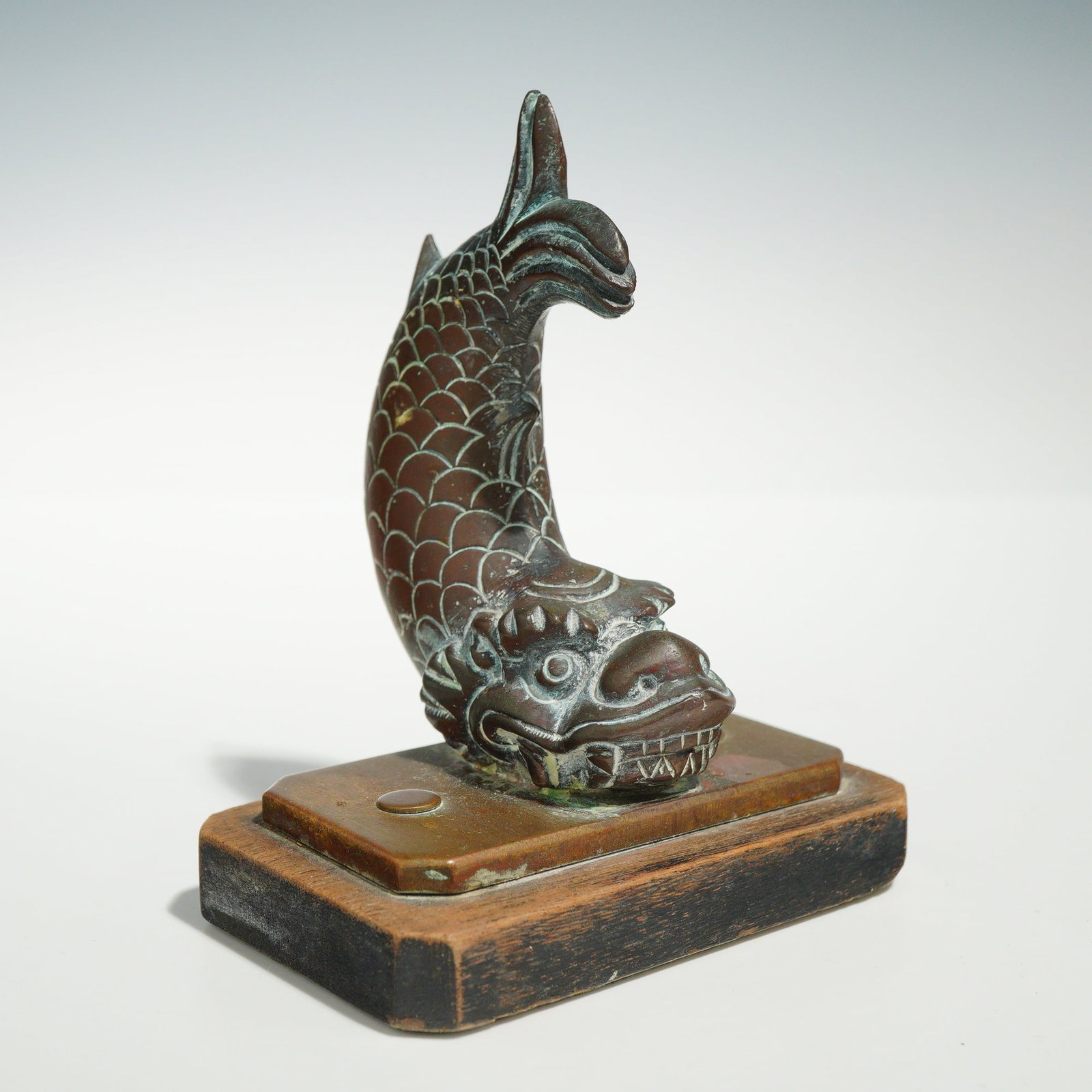 Japanese Bronze Shachihoko Dragon Fish Sculpture on Stepped Base: A Japanese cast metal decorative sculpture depicting a shachihoko, a mythical creature with the head of a dragon and the body of a carp. The figure is modeled in a traditional vertical posture with it