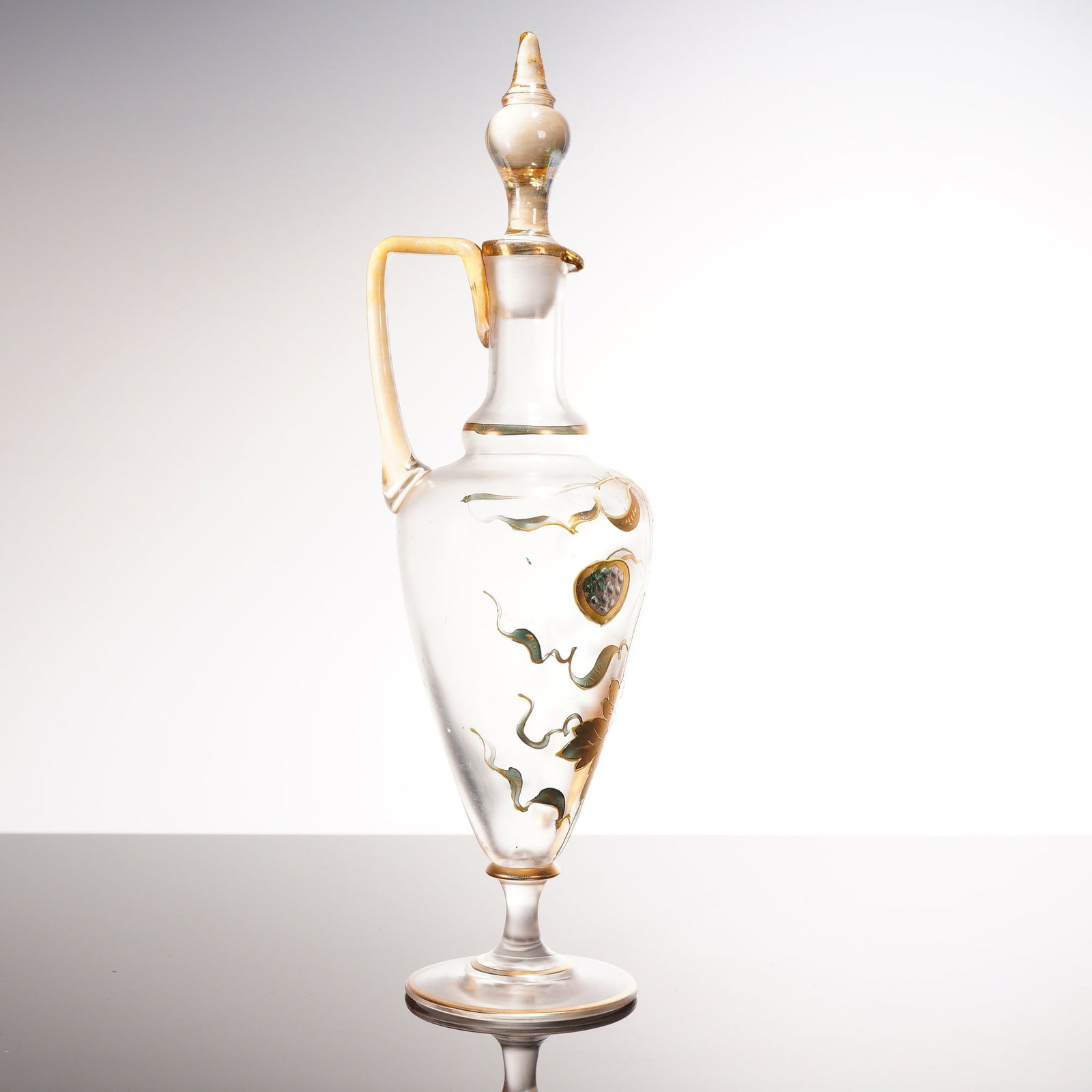 Bohemian Art Nouveau Enameled and Gilded Glass Claret Jug with Stopper: A fine late 19th or early 20th-century Art Nouveau hand-blown glass claret jug or ewer, likely of Bohemian origin. The vessel features a tapered clear glass body with an applied amber-colored glass