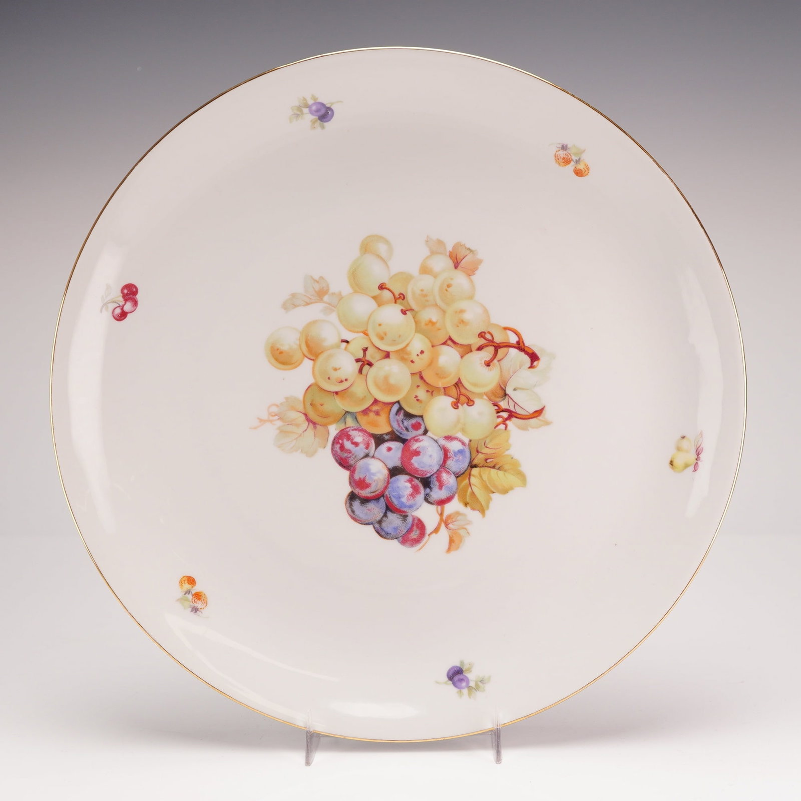 Schumann Arzberg German Porcelain Fruit Motif Charger from the Rubin Collection: Attributed to Schumann Arzberg, this German porcelain charger is part of the Rubin Collection. The piece features a central polychrome decoration of a grape cluster in shades of purple, green, and