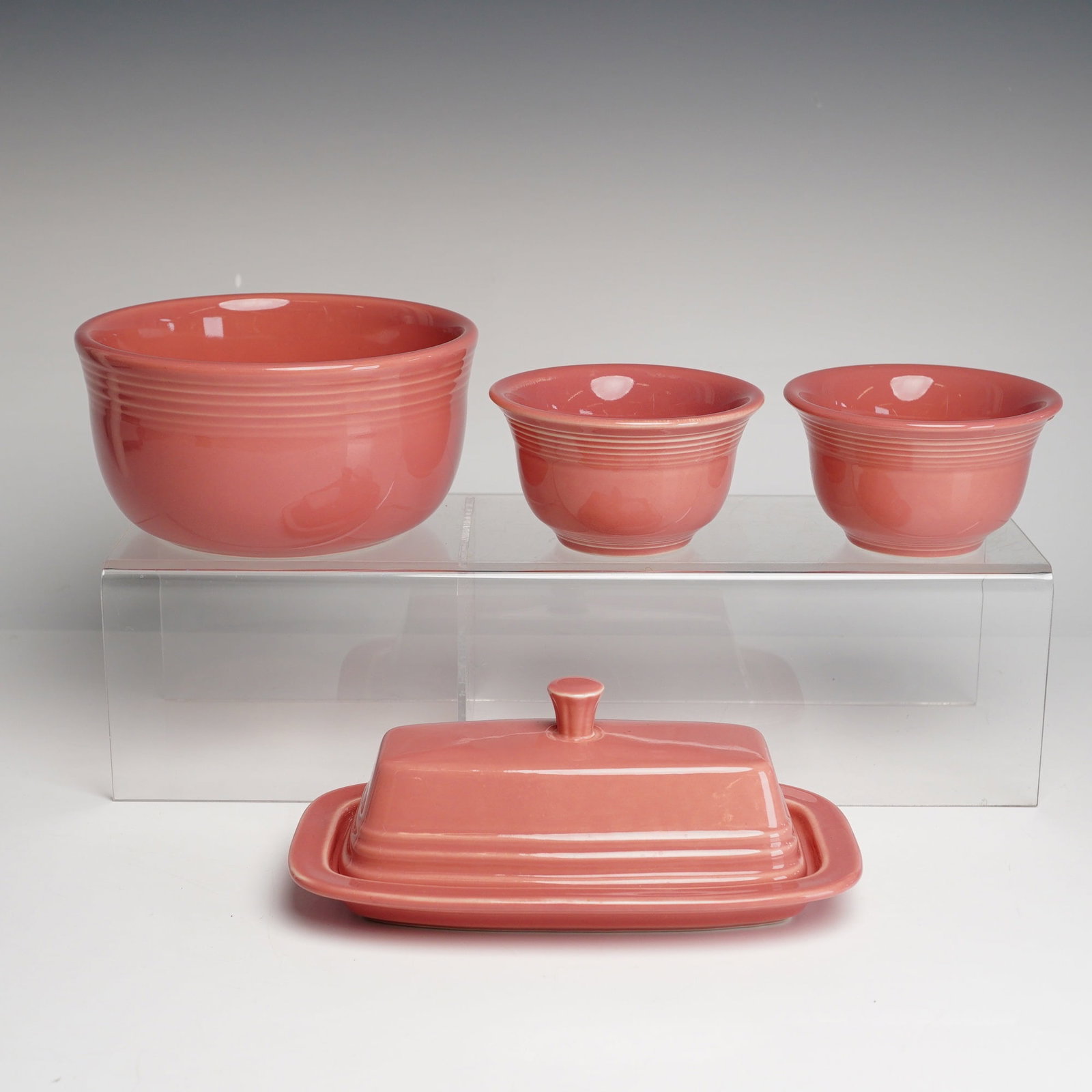 4pc FiestaWare Serving Bowl, Condiment Bowls & Covered Butter Dish: A four-piece collection of glazed ceramic tableware manufactured by the Homer Laughlin China Co. as part of the iconic Fiesta line. The grouping is finished in the soft pink Rose hue. Each piece featu