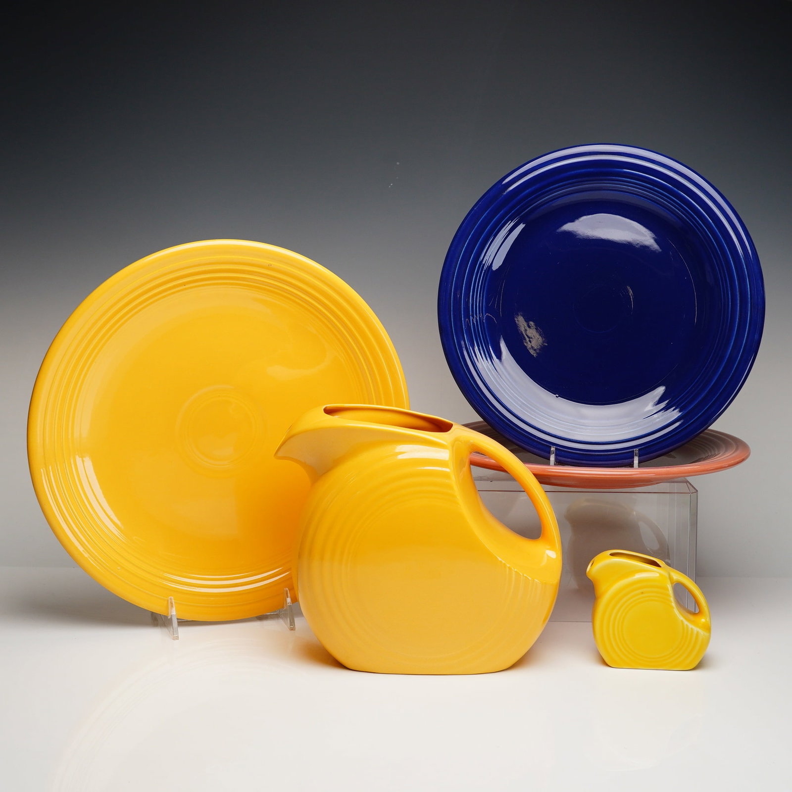 5pc Homer Laughlin Fiesta Ware Pitcher, Creamer, Luncheon & Dinner Plates: A collection of five glazed ceramic tableware pieces from the iconic Fiesta line by the Homer Laughlin China Co. This group exemplifies the Art Deco aesthetic with its signature concentric ring patter