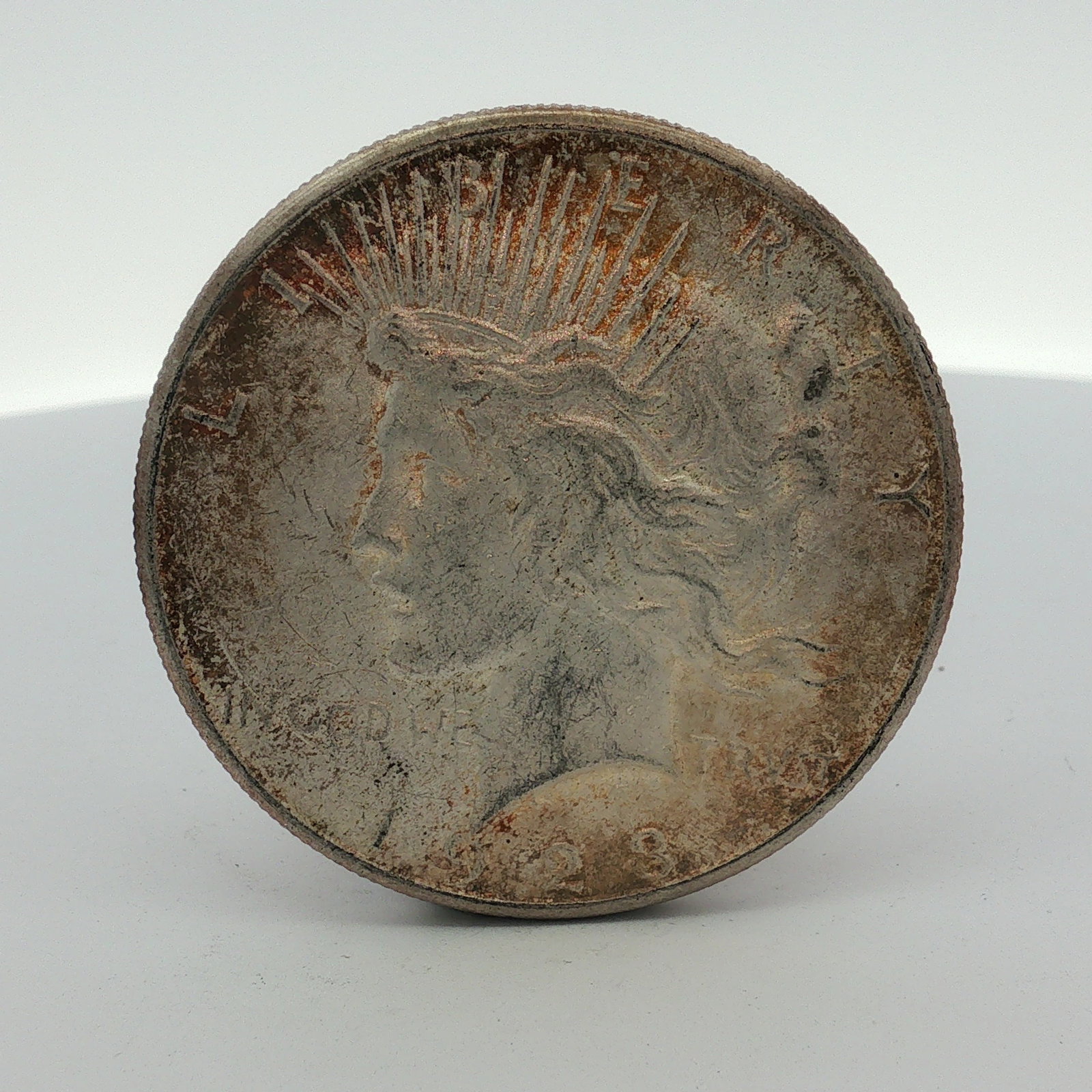 1923-S US One Dollar Peace Silver Dollar Coin, Circulated: 1923 US Peace silver dollar. This coin is composed of 90 percent silver and 10 percent copper. It was struck at the San Francisco Mint as evidenced by the S mint mark by the Eagles tail feathers. The 