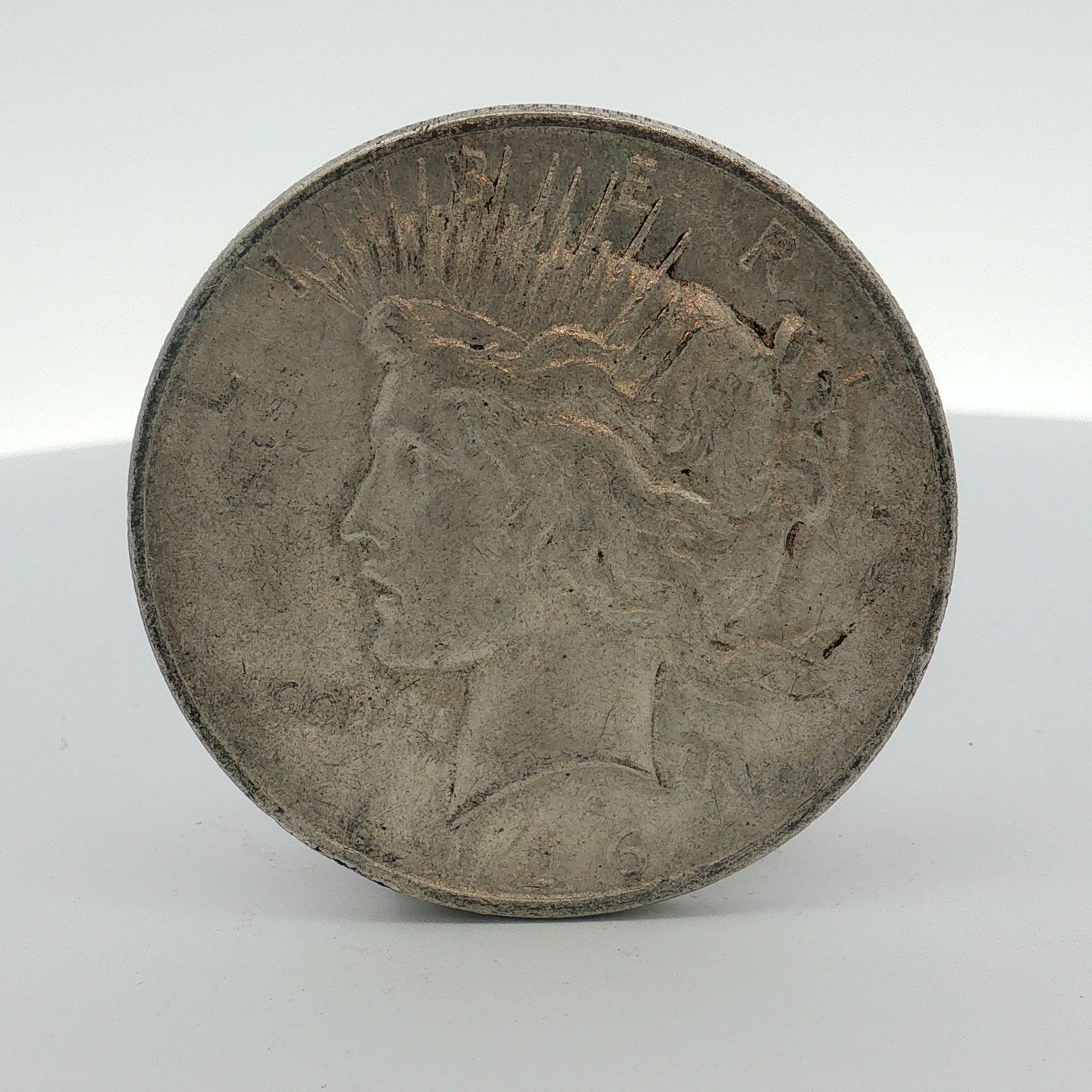 1926-D US One Dollar Peace Silver Dollar, Circulated: This 1926-D US Peace silver dollar was produced at the Denver Mint. The coin is composed of a 90 percent silver and 10 percent copper alloy. It features the standard Peace dollar design on the obverse