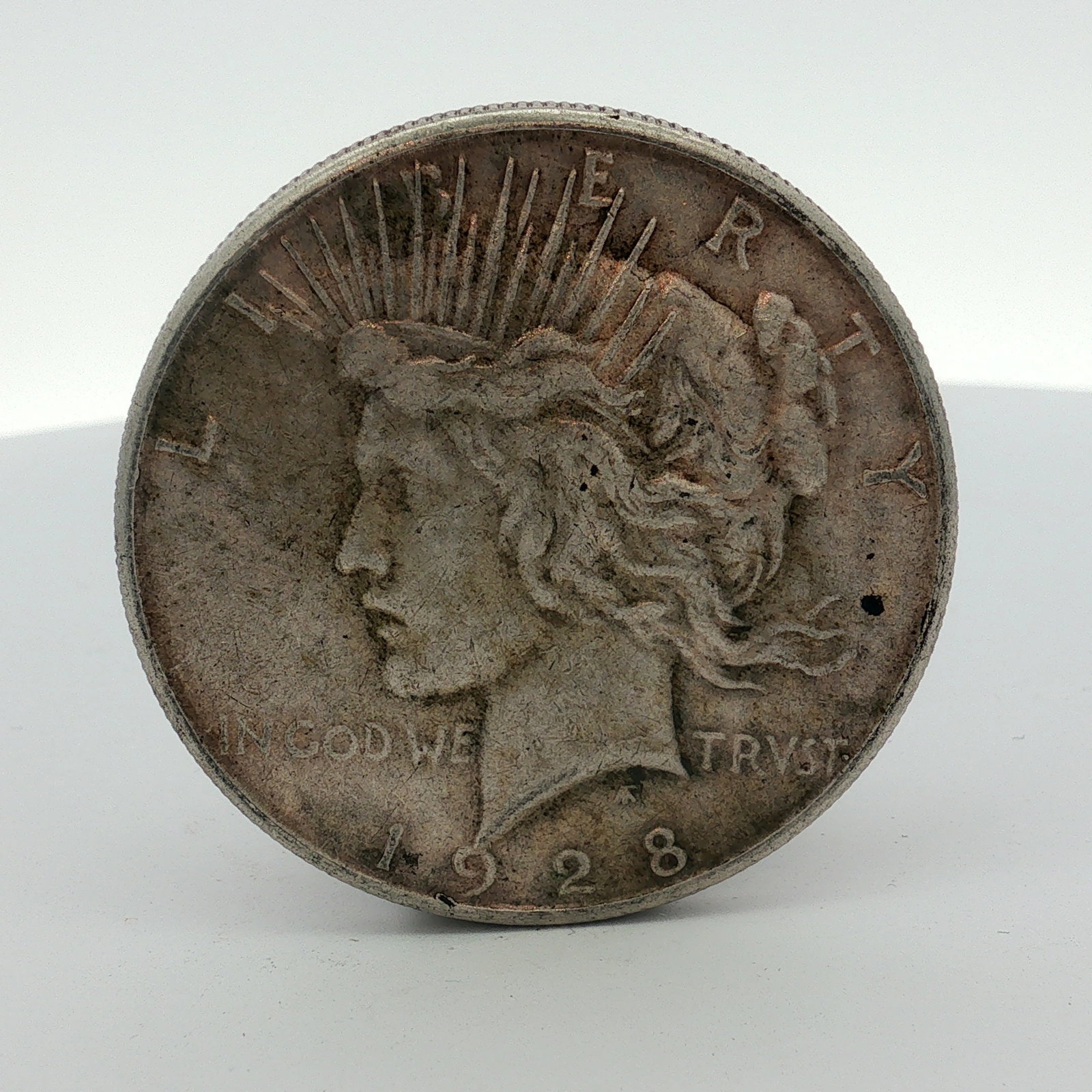 US 1928-S Silver Peace Dollar: A US 1928-S silver Peace dollar minted at the San Francisco Mint. The obverse features the left-facing head of Liberty wearing a radiate crown, with the inscriptions LIBERTY, IN GOD WE TRVST, and the 