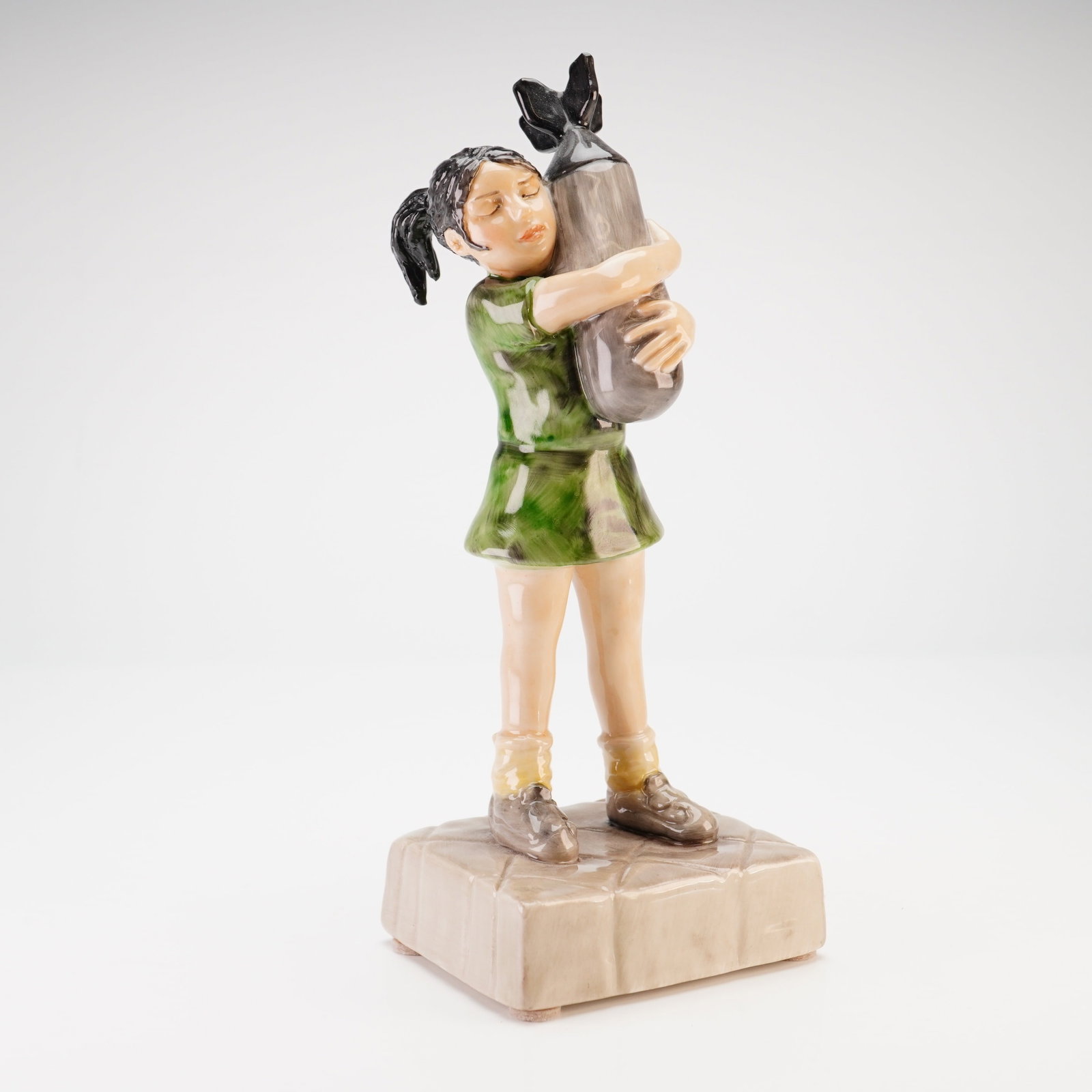 Banksy Bomb Hugger by Kevin Francis Signed Trial Edition Ceramic Figurine: A Kevin Francis glazed ceramic figurine titled Bomb Hugger, representing a three-dimensional interpretation of the motif originally created by the street artist Banksy. The sculpture depicts a young