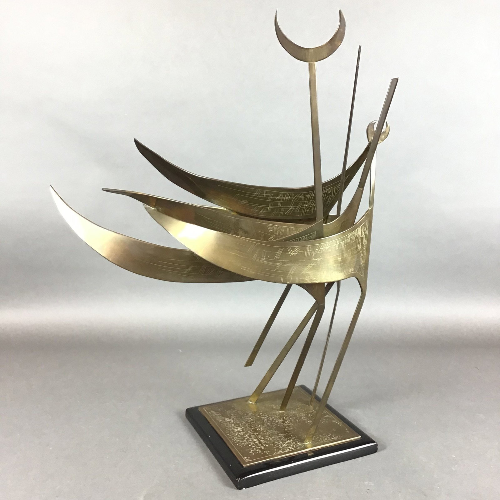 Paul Jeffries Abstract Metal Sailboat Sculpture: This mid-to-late 20th-century abstract metal sculpture is the work of artist Paul Jeffries. The artwork is constructed from brass or bronze with a gold-tone finish, featuring sweeping, sail-like