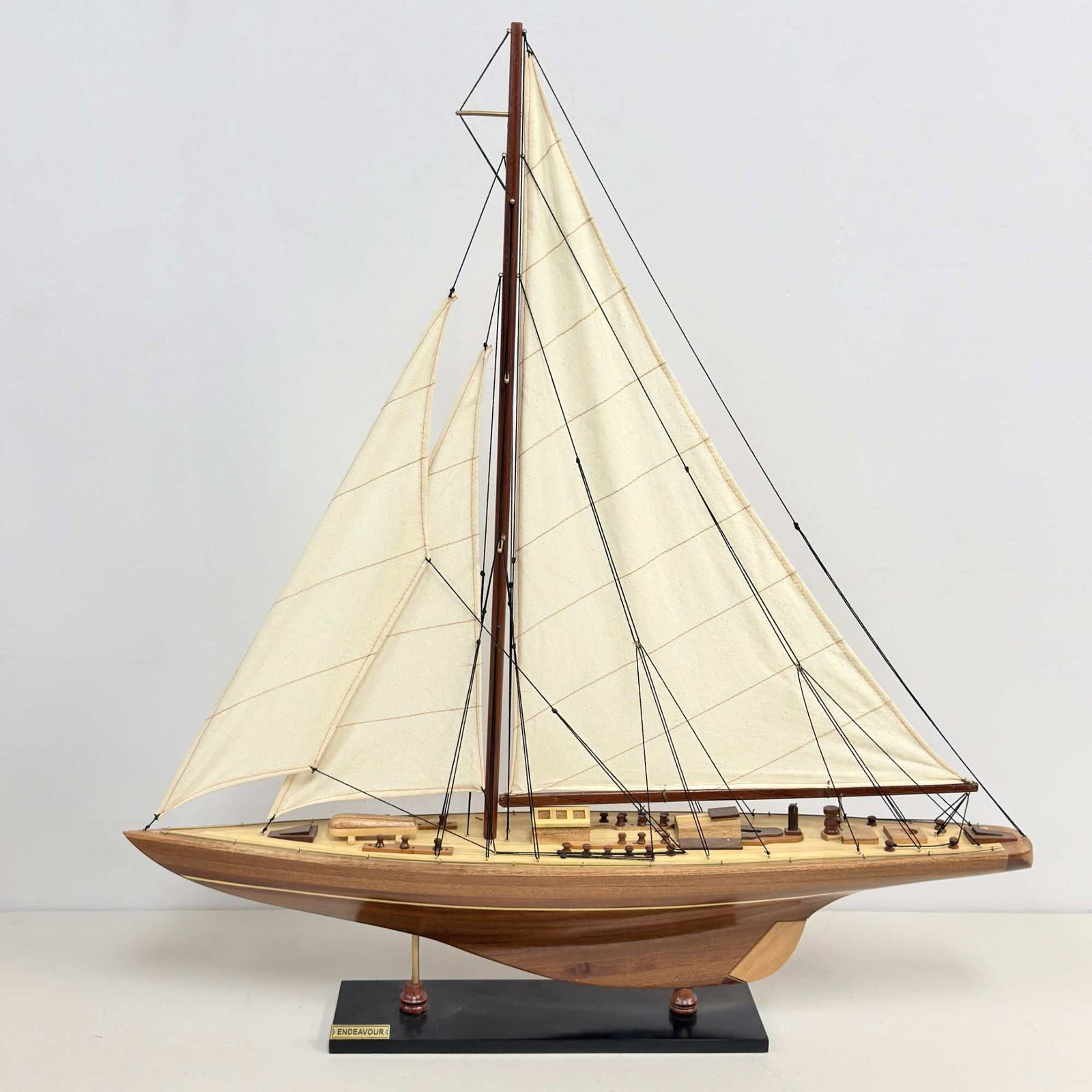 Endeavour J-Class Yacht Handcrafted Model Replica: This is a handcrafted wooden display model of the J-class racing yacht Endeavour. The model features a plank-on-frame style hull with a high-gloss polished finish and a light-colored wood deck. Deck