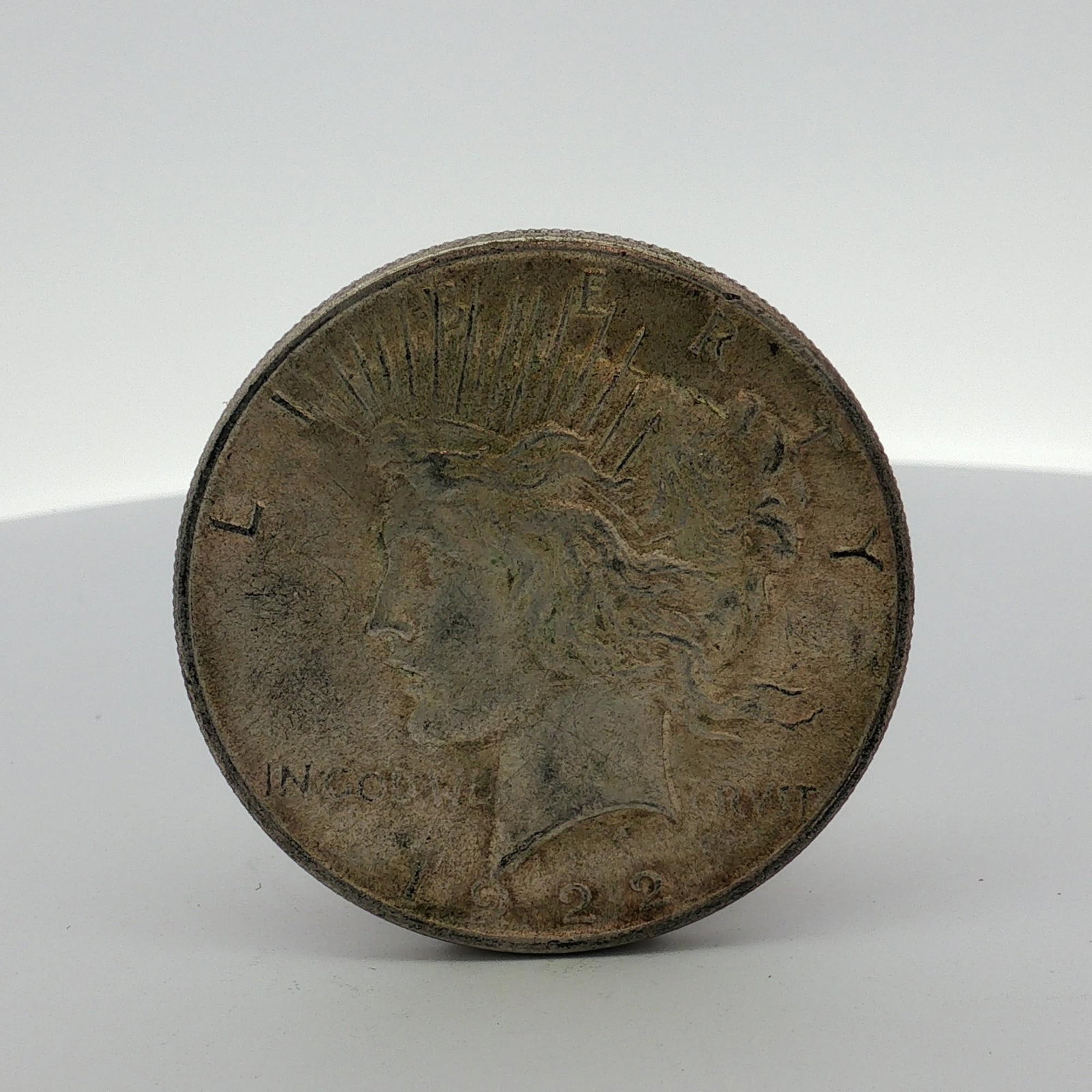 1922 US Peace Silver Dollar: This United States 1922 Peace silver dollar was struck at the Philadelphia Mint. The coin features the standard Peace dollar obverse and reverse designs. It is composed of 90 percent silver and 10 per