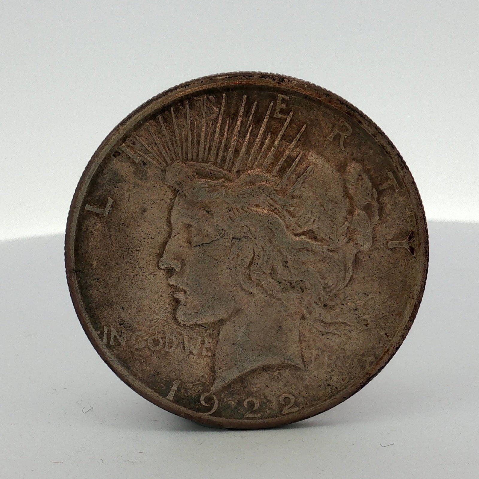 1922-S US Peace Silver Dollar: 1922 US Peace silver dollar struck in .900 fine silver. The obverse features the Peace dollar design with inscriptions LIBERTY, IN GOD WE TRVST, and the date 1922. The reverse includes the inscription