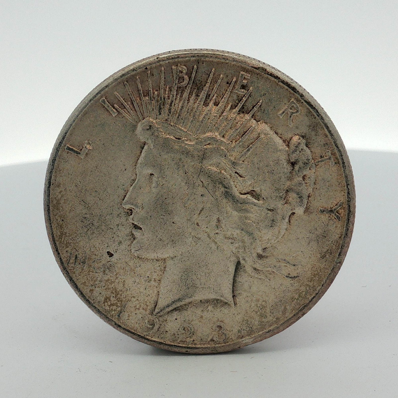 1923-S US Peace Silver Dollar: This 1923-S US Peace silver dollar is composed of 90% silver and 10% copper. The coin was struck at the San Francisco Mint, identified by the S mint mark on the reverse. It features the standard