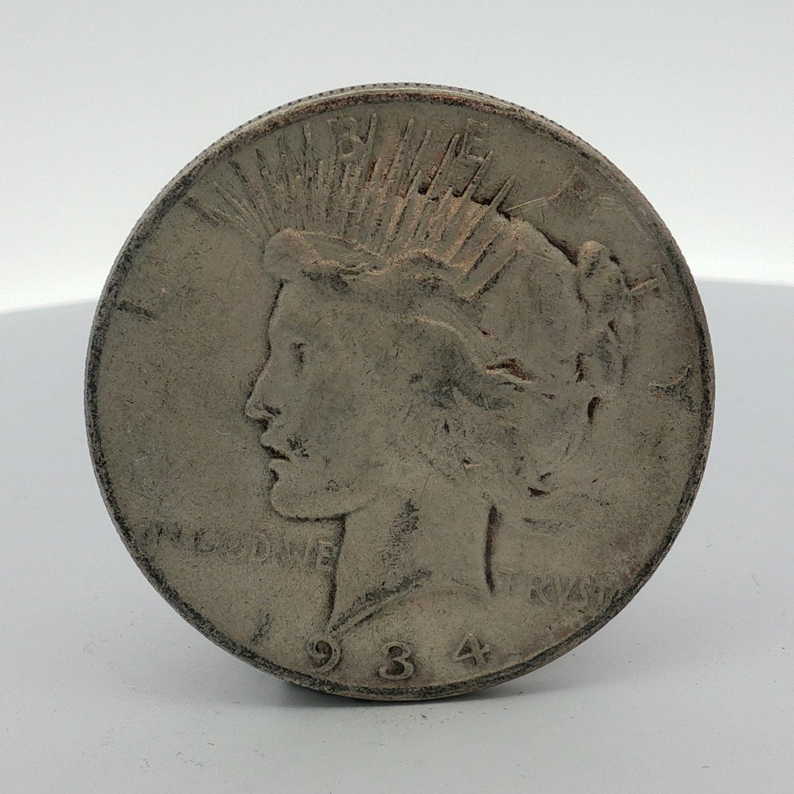 1934-S US One Dollar Peace Silver Dollar Coin, Circulated: This United States silver one dollar coin is part of the Peace Dollar series, dated 1934. It was struck at the San Francisco Mint, as indicated by the S mint mark on the reverse. The coin is composed 