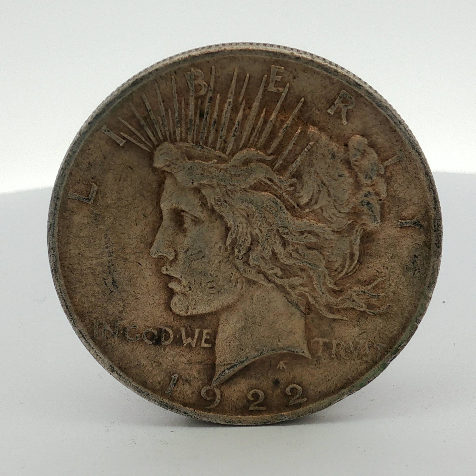 US 1922 Peace Silver Dollar: This US 1922 Peace silver dollar was struck at the Philadelphia Mint, as identified by the absence of a mint mark. The coin is composed of 90 percent silver and 10 percent copper. It features a