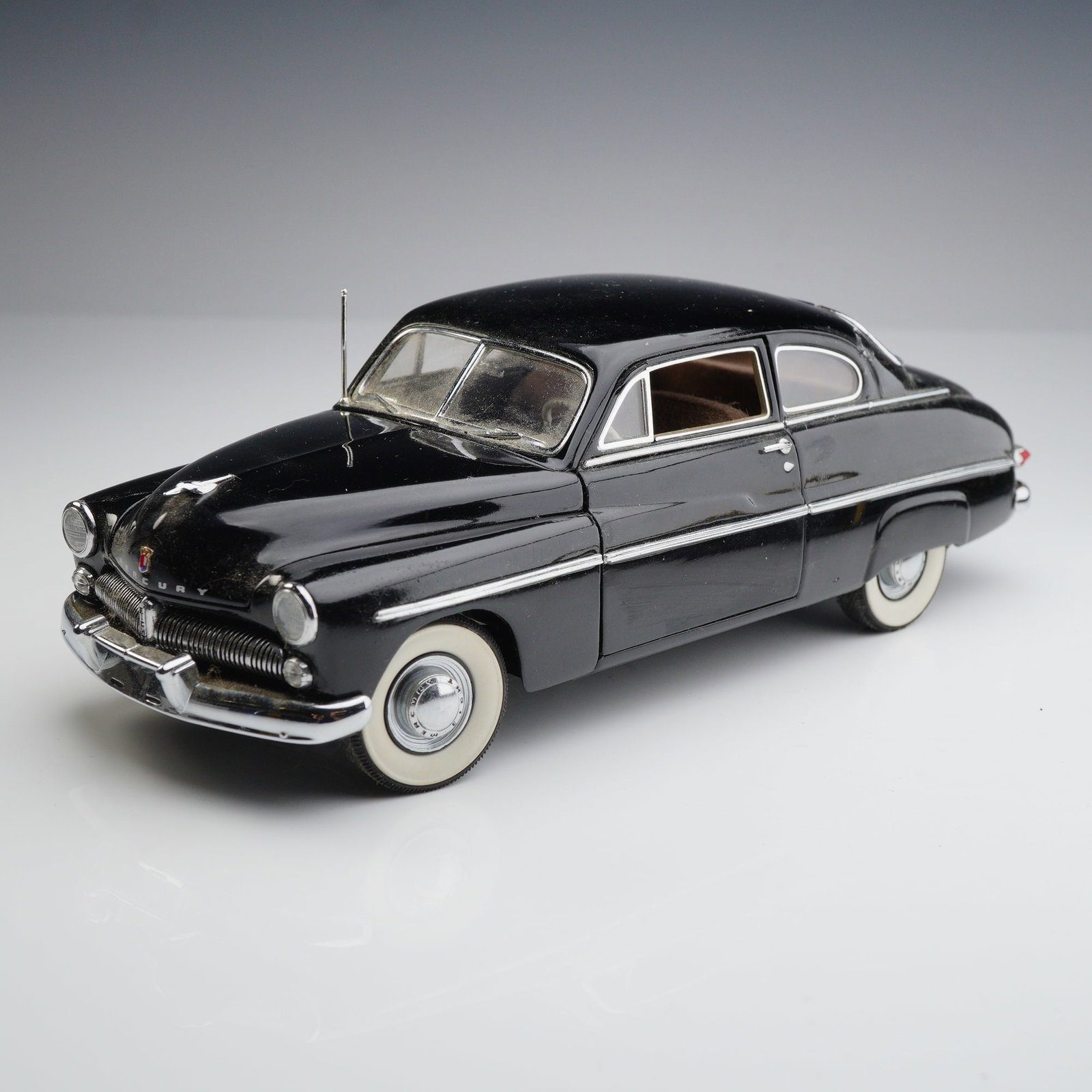 Danbury Mint Classic Cars Collection 1949 Mercury Club Coupe: This die-cast model represents a 1949 Mercury Club Coupe from the Danbury Mint Classic Cars Collection, produced at a 1:24 scale. The vehicle features a black exterior finish with chrome-plated