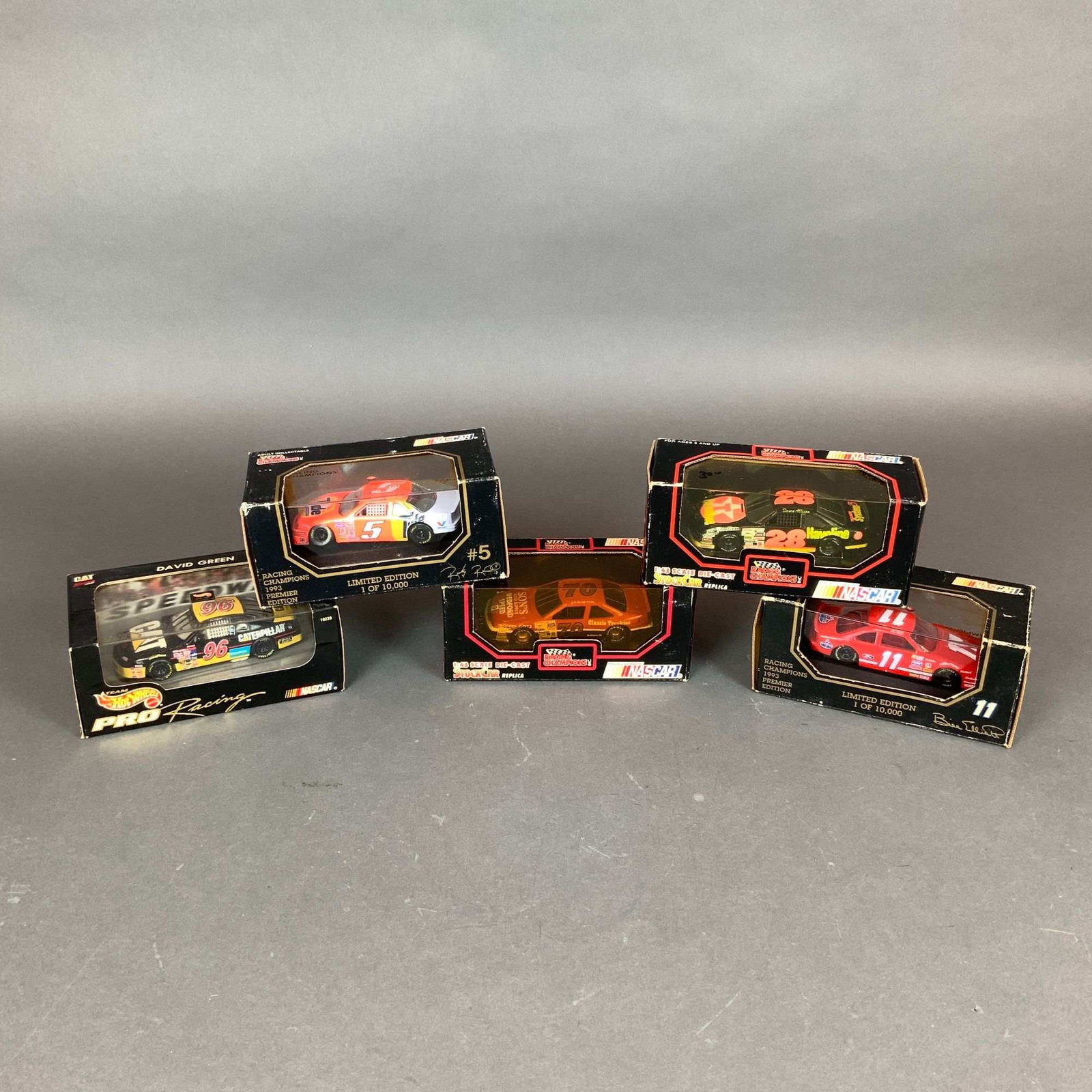 Five 1:43 Scale NASCAR Die-Cast Model Cars Including Hot Wheels and Racing Champions: A collection of five 1:43 scale NASCAR die-cast model cars in original display packaging, featuring manufacturers Racing Champions and Hot Wheels PRO Racing. The lot includes a David Green number 96